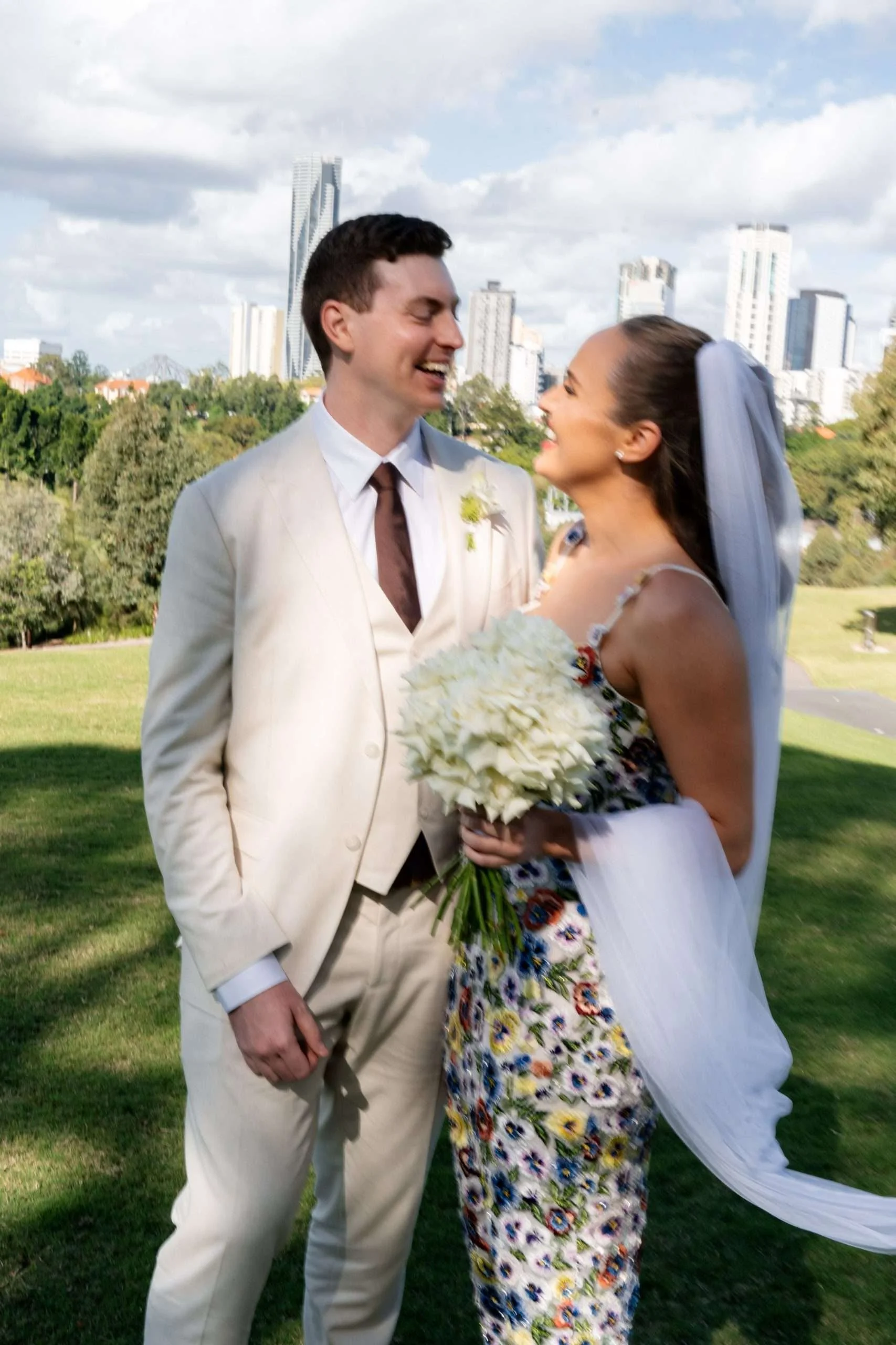 Bride and groom laughing at each other while holding one another close.