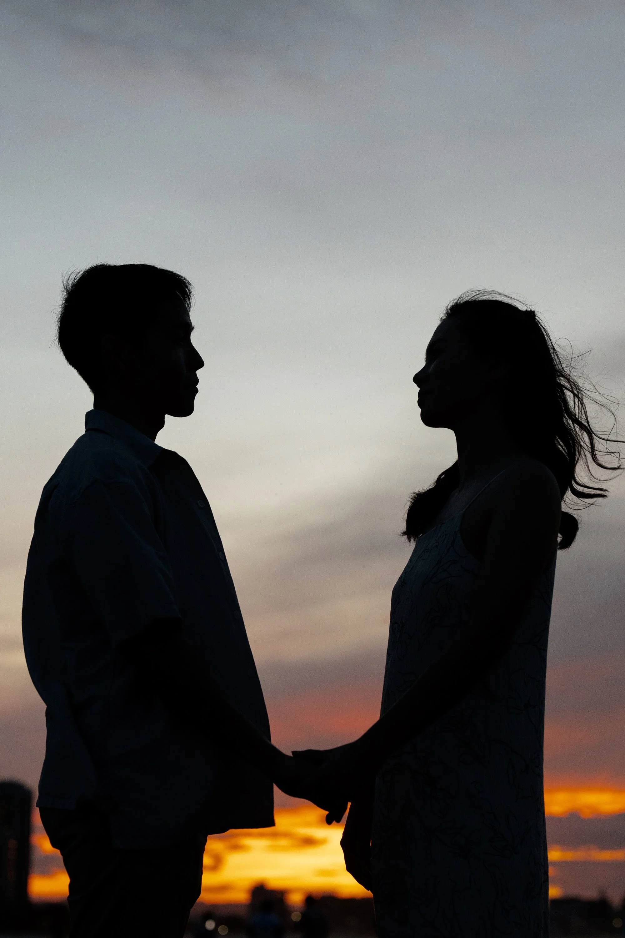 Krystel and Paul holding hands and look at each other under sunset in Currumbin Rock
