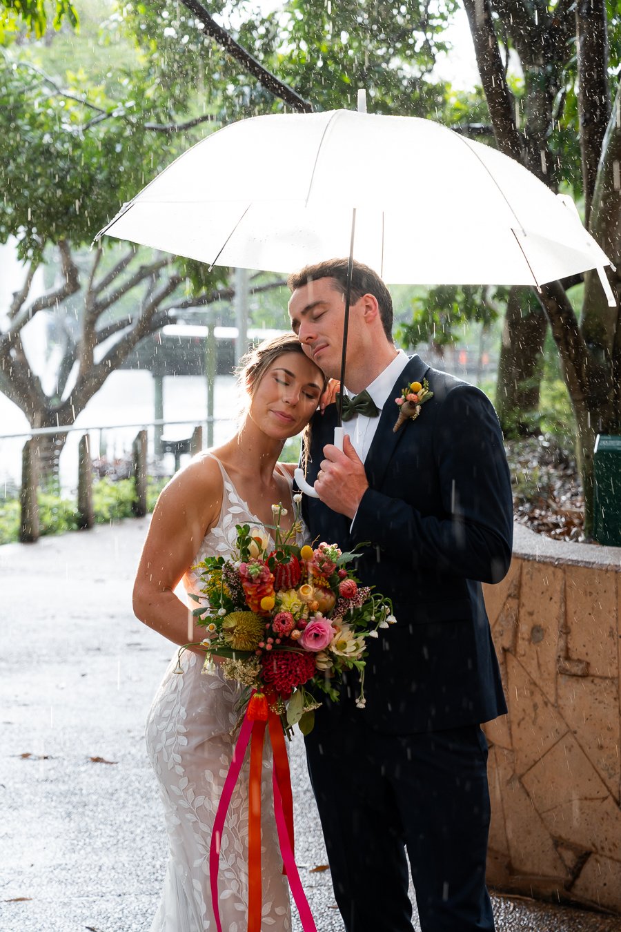 bride Sonya rest her head on Giordan's shoulder when he holding a umbrella in a raining time