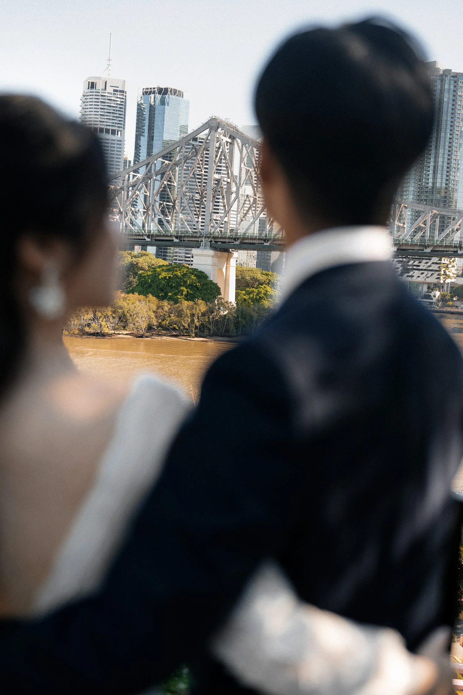 bride Cassie and groom Leo holding each other look at the Brisbane story bridge
