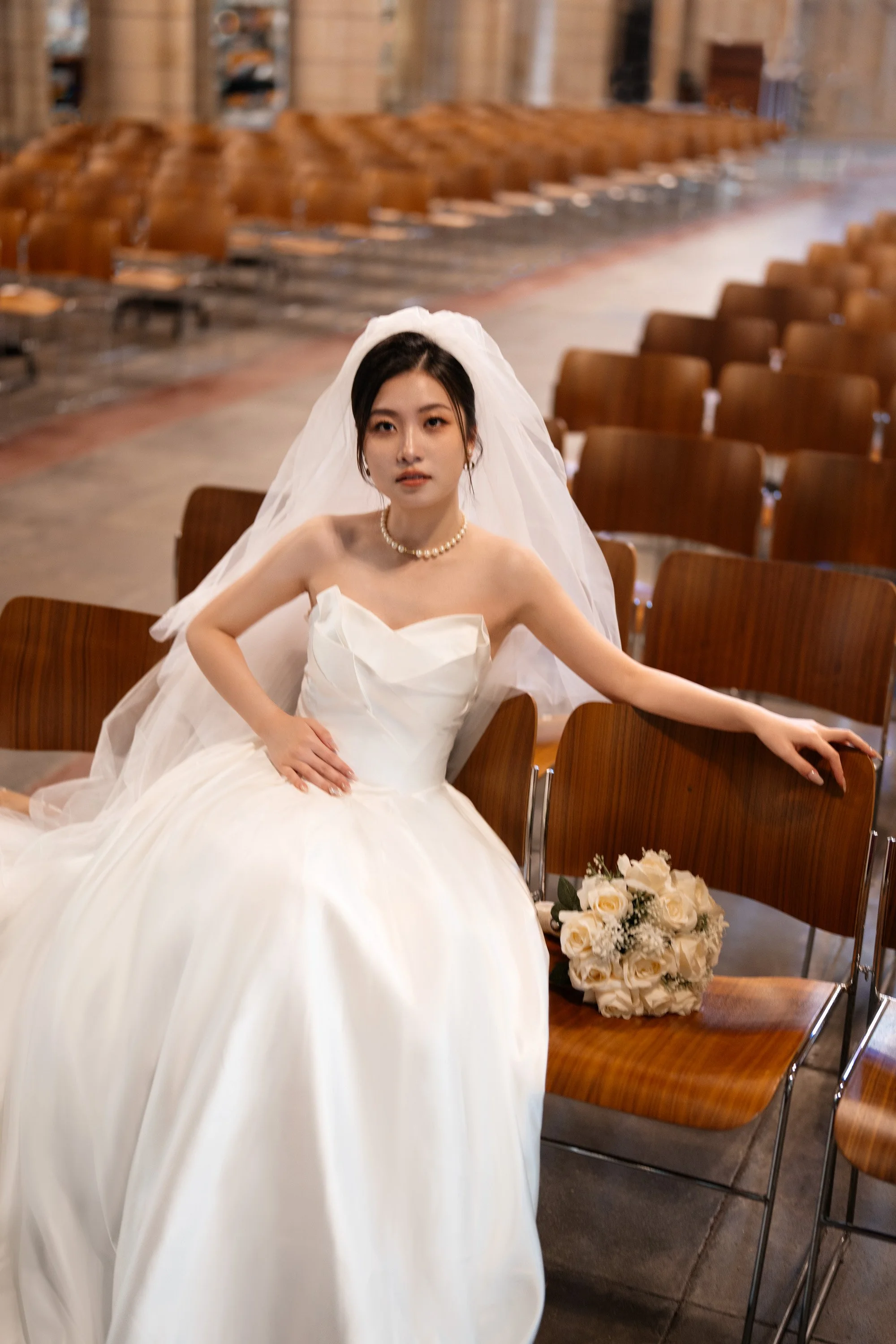 bride Cassie touching her belly and look at the Brisbane wedding photographer Whistler when sitting on the chair