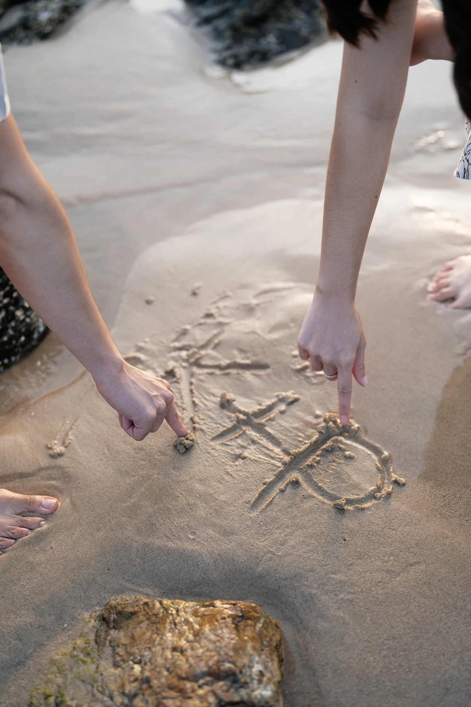 Krystel and Paul name initial letter written on the sand K+P