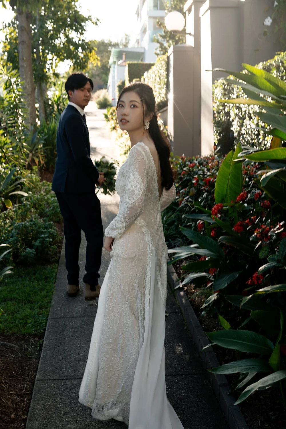 bride and groom walking on a pathway and bride Cassie look back to the camera