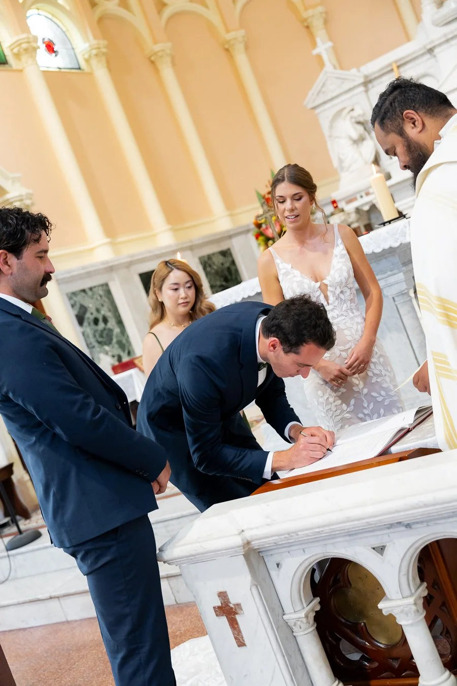 best man signing the marriage certificate and bride and groom look at him