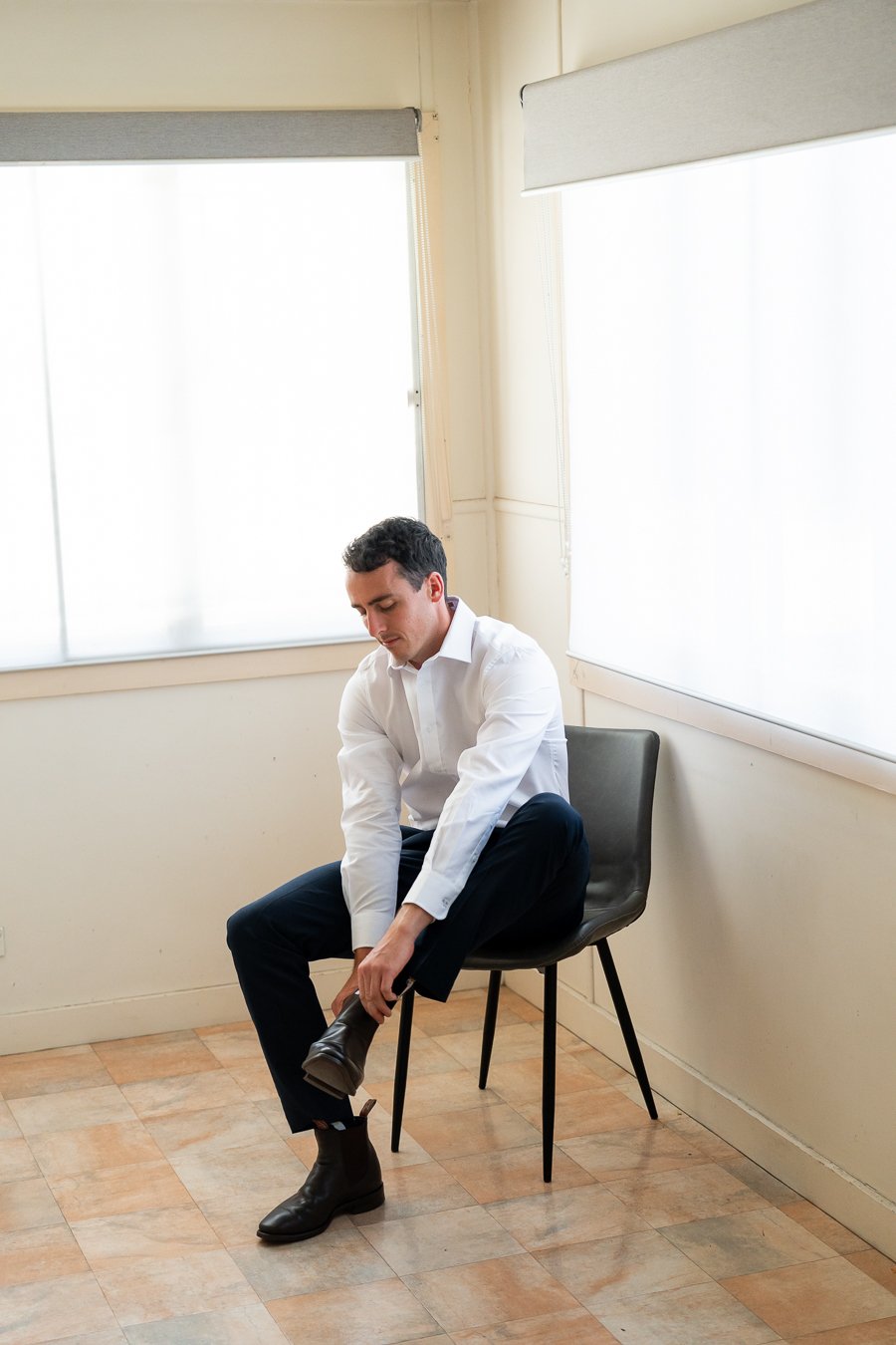 The groom sat on a bench, putting on his shoes.