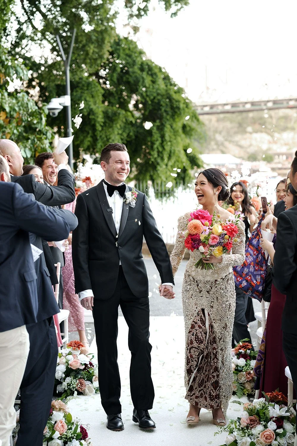 Nori and Cliffe holding hands walking down the aisle with paddles up to the air