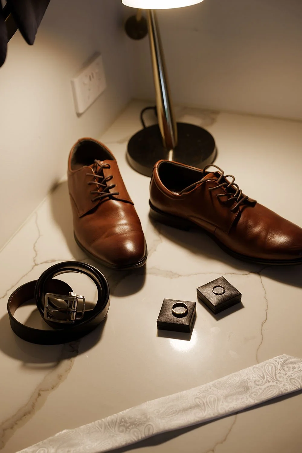 shoes, wedding rings, belt and tie on the table