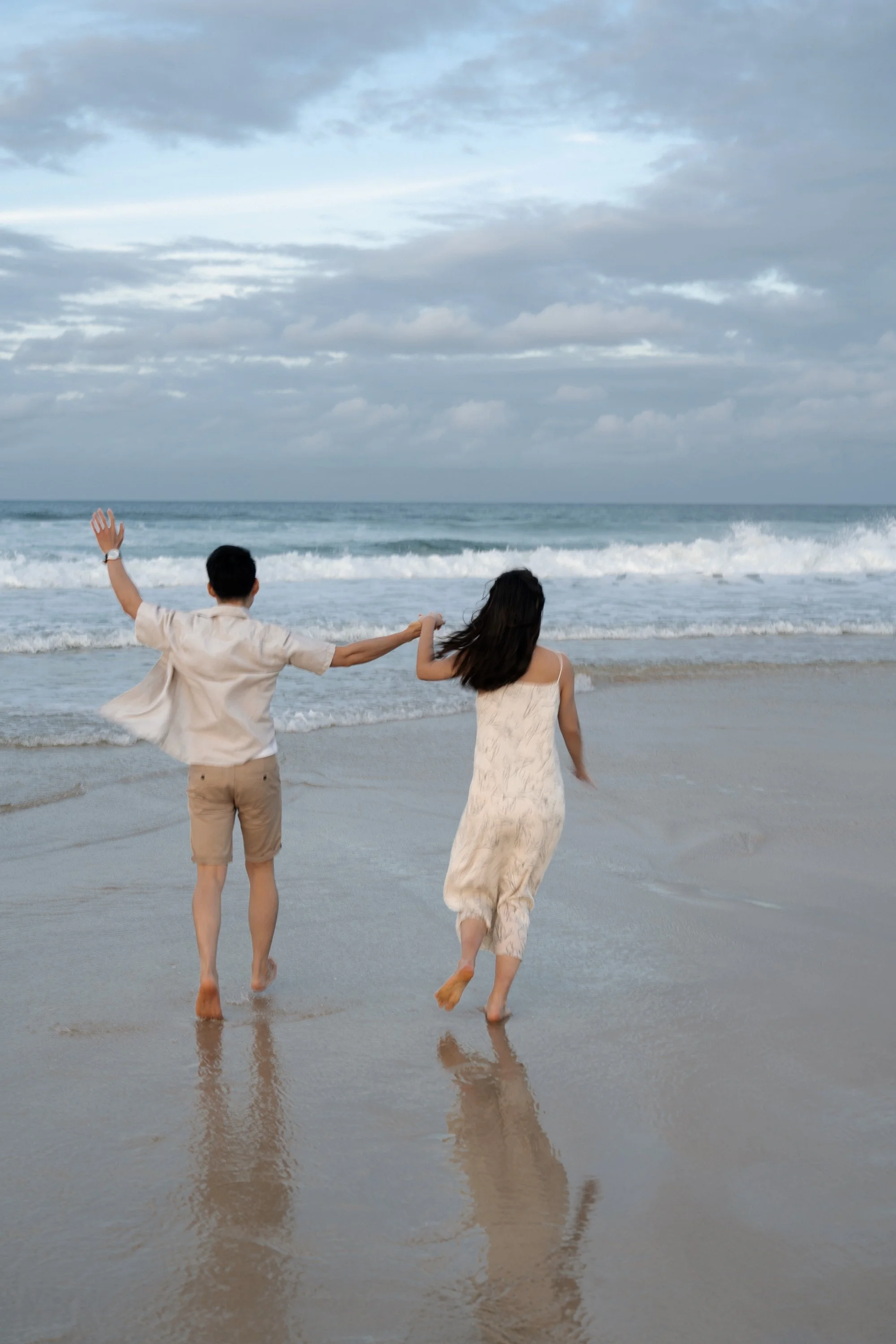 Paul and Krystel holding hands running towards to the ocean in Gold Coast Currumbin Alley