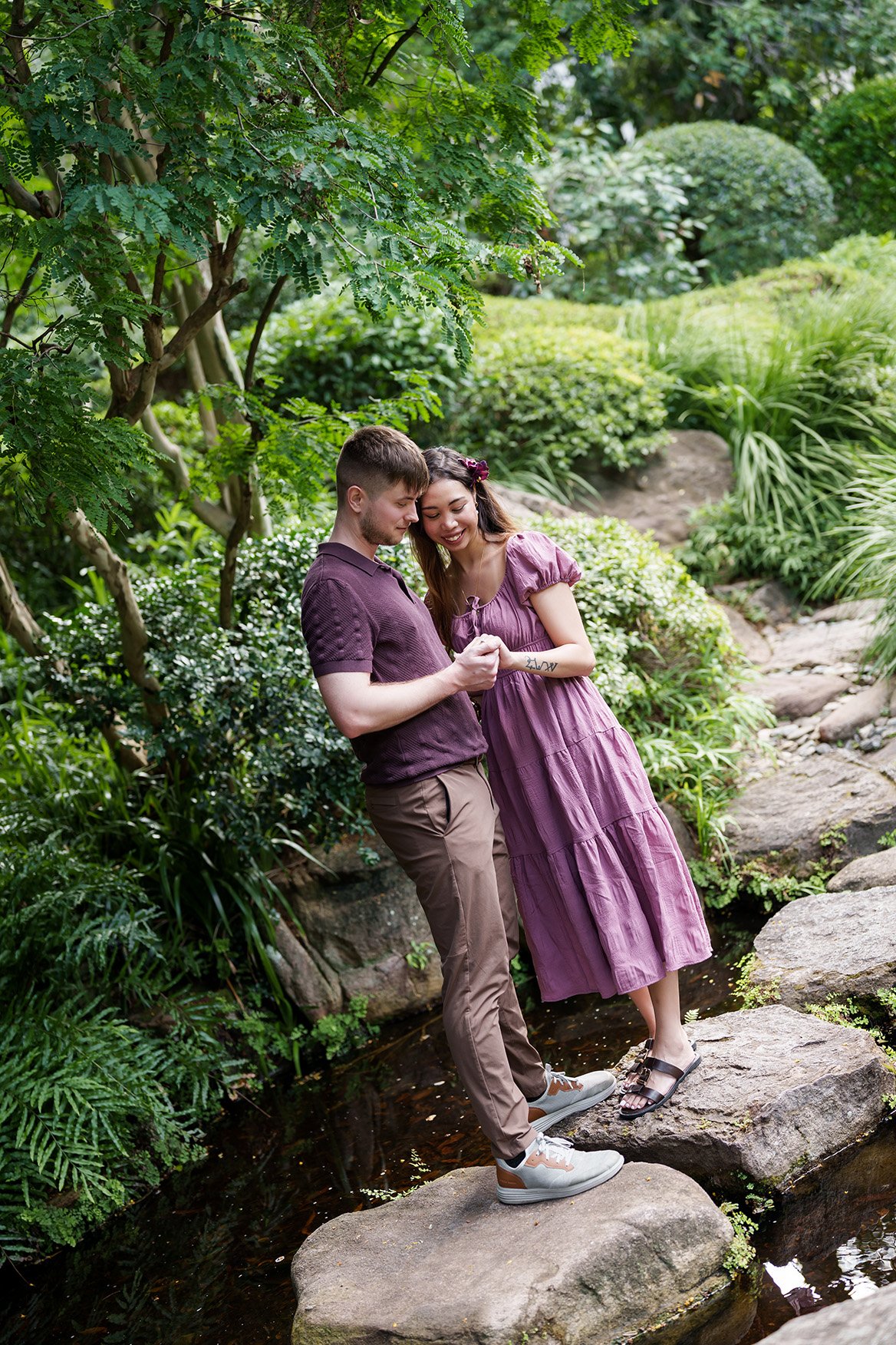 Ruby and Kyle holding hands while look at them, stand next to each other on rocks