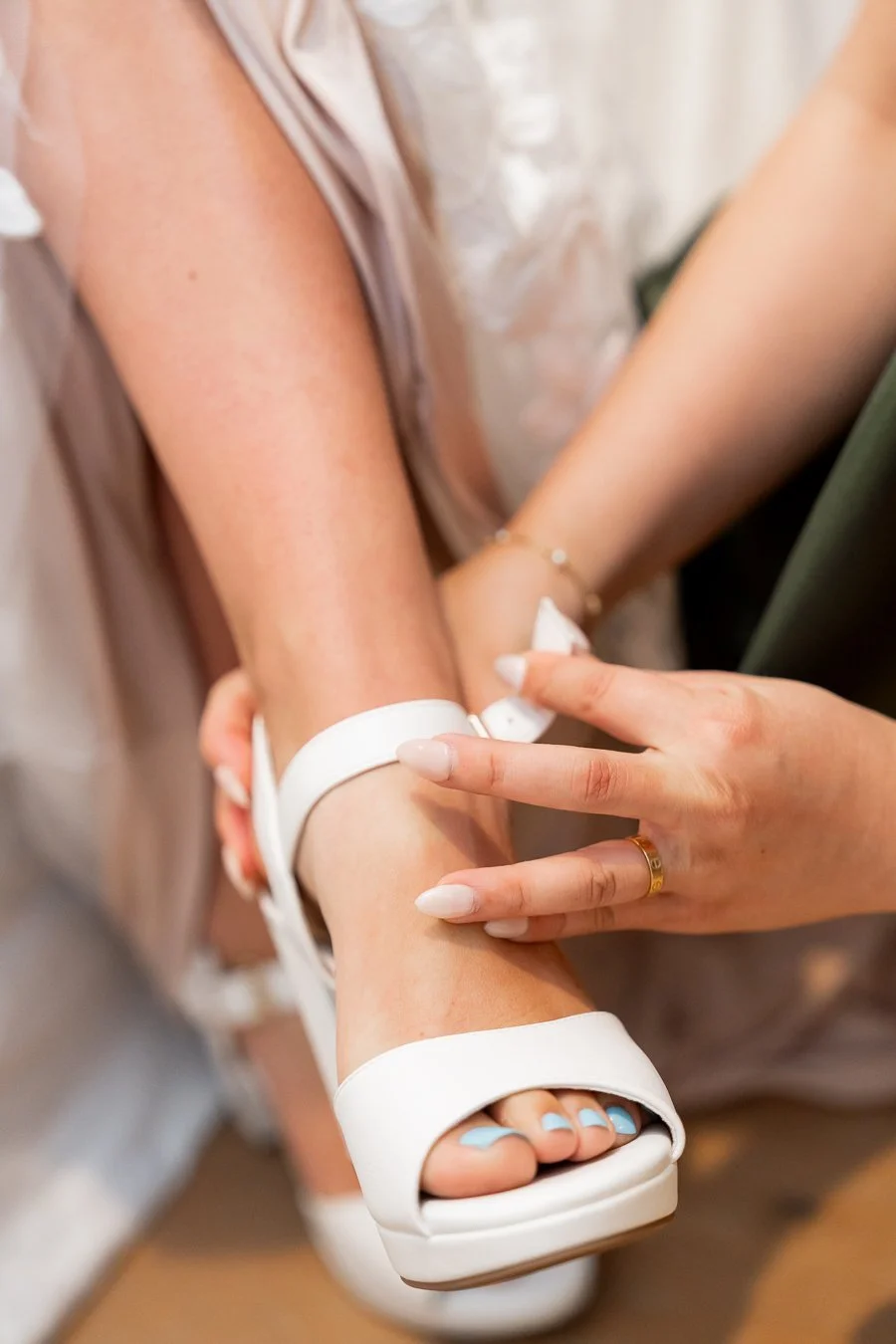 The maid of honor helped the bride put on her shoes