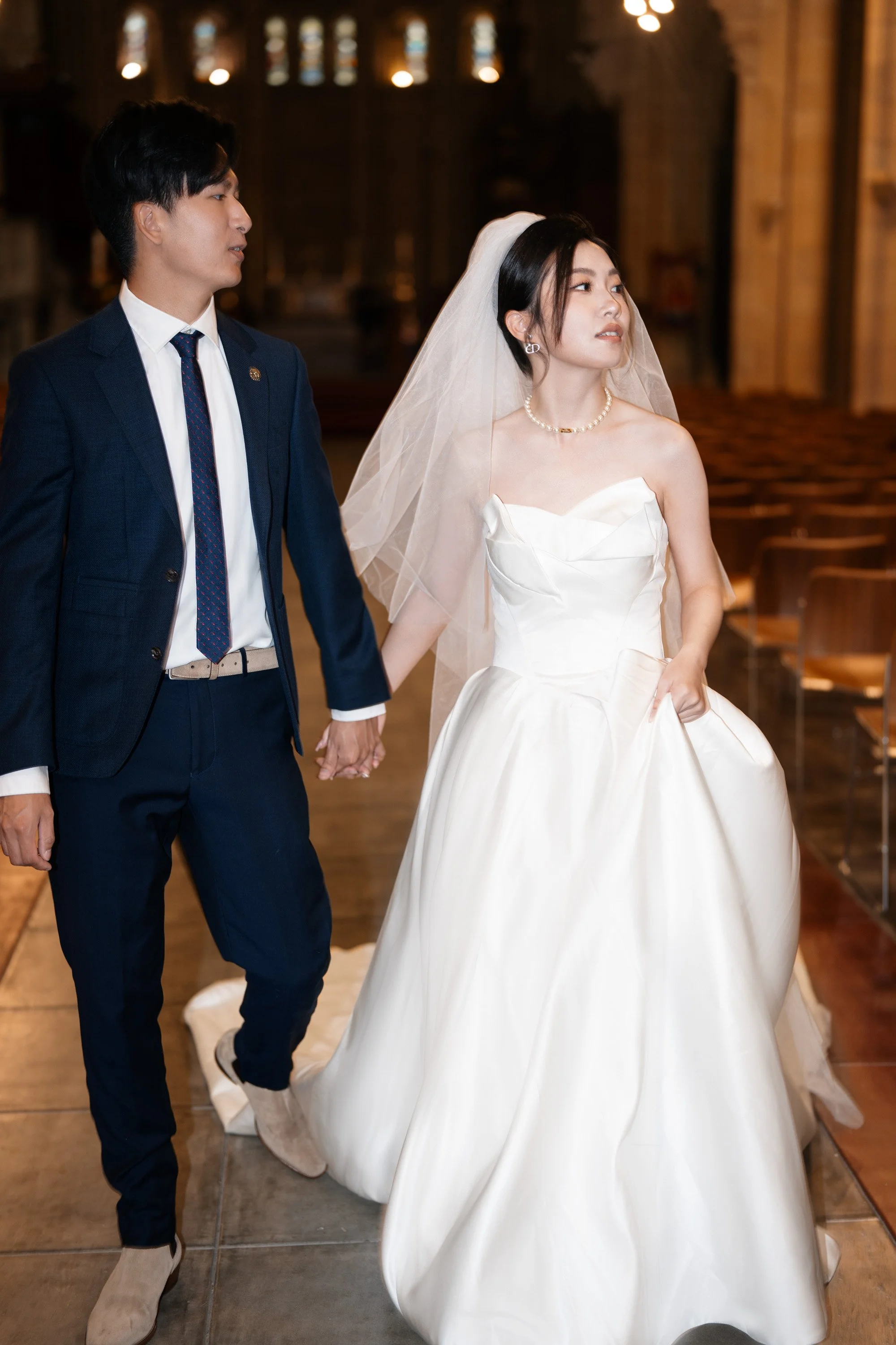 bride and groom holding hands walking towards to the camera and look away