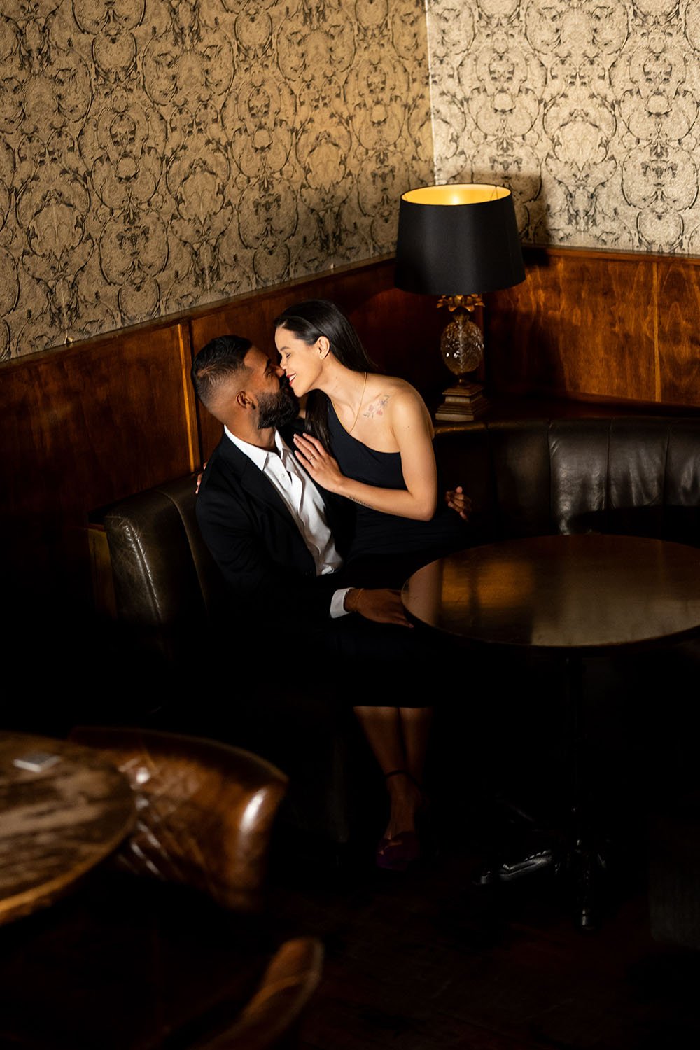 Jasmin and Jay nose touching while sitting on a leather sofa