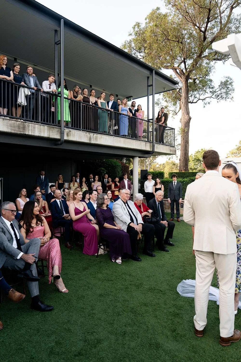 bride and groom holding hands in front of arbor with all guest in wedding ceremony in Victoria park