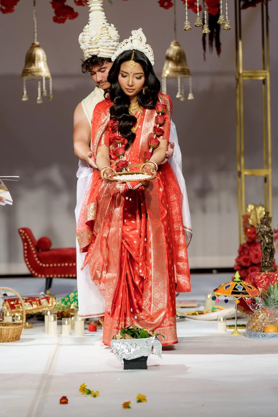 Amrita pull some rice into fire and Casey stand behind her