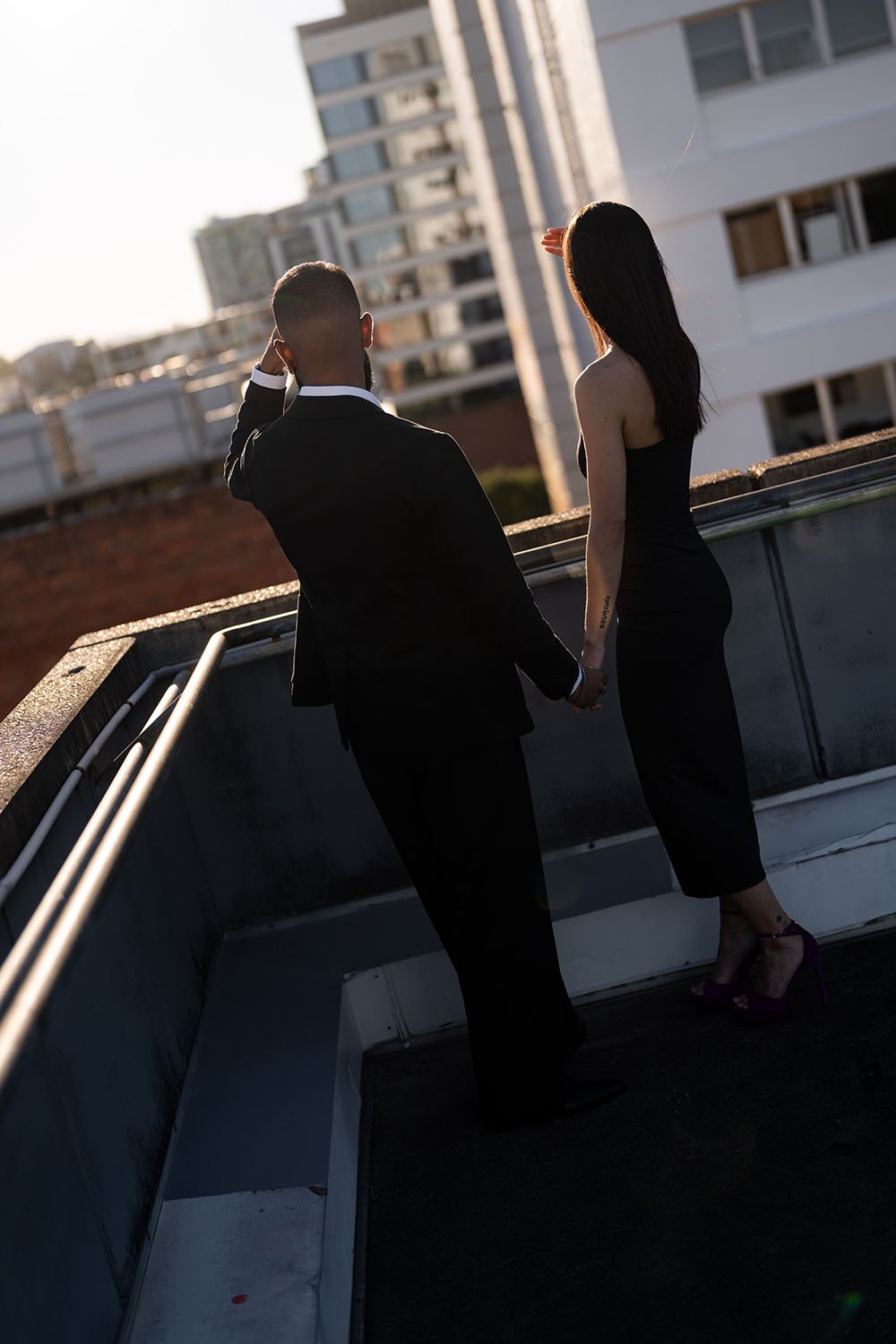 Jasmin and Jay hold hands look towards to the building side