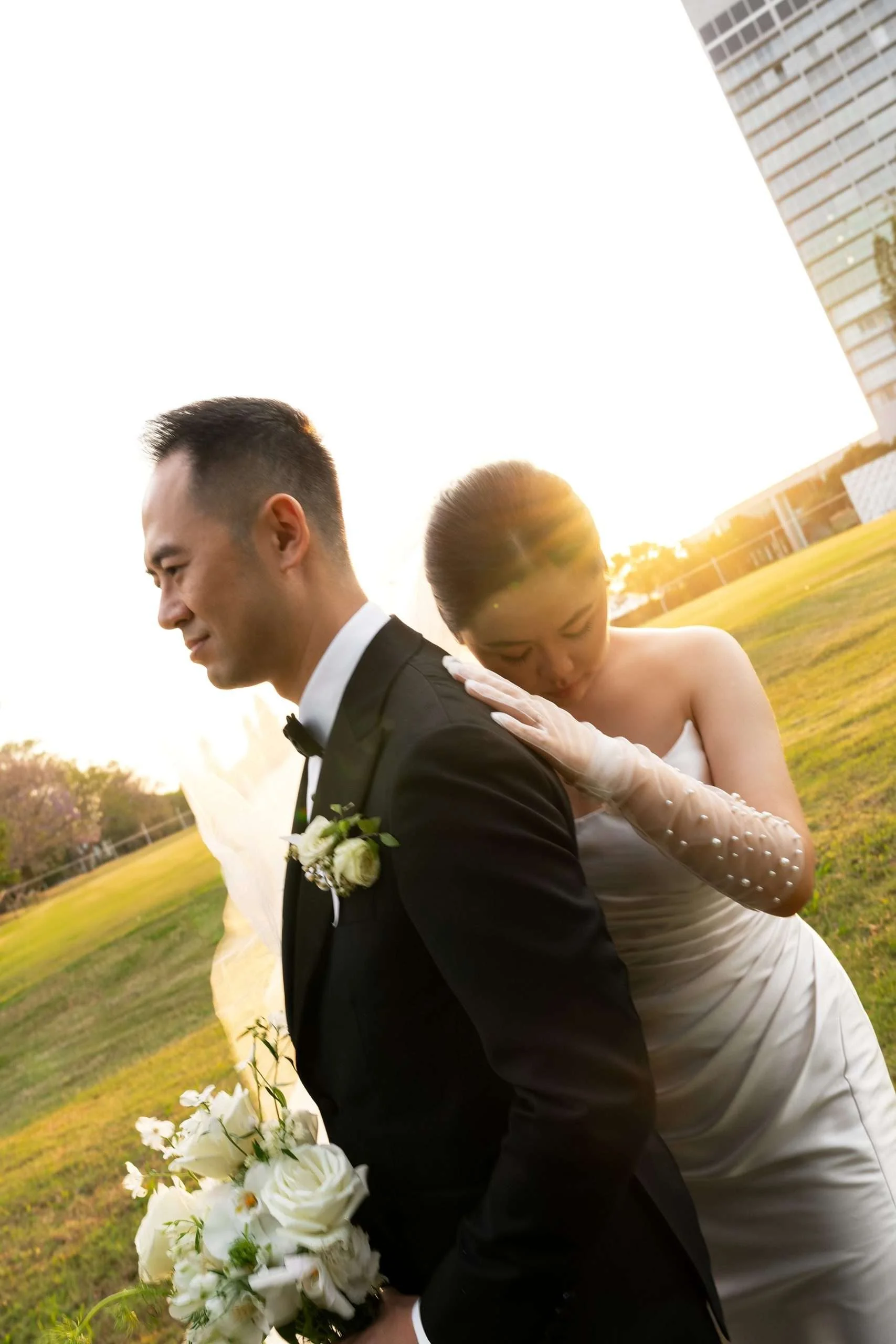 Wendy at Alex's back with one hand touching his shoulder while look down to the grass