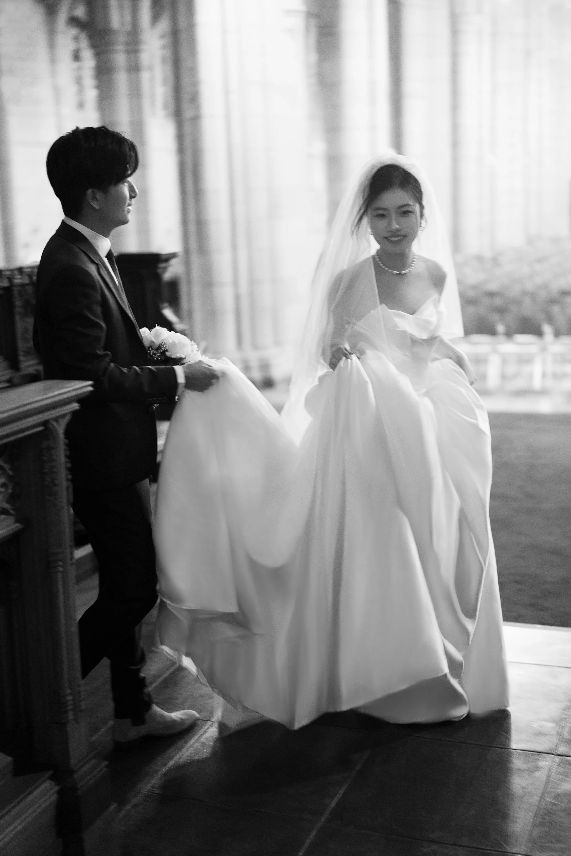 Leo holding Cath's dress trial and look at her while they walking foreward captured by Brisbane wedding photographer Whistler Li