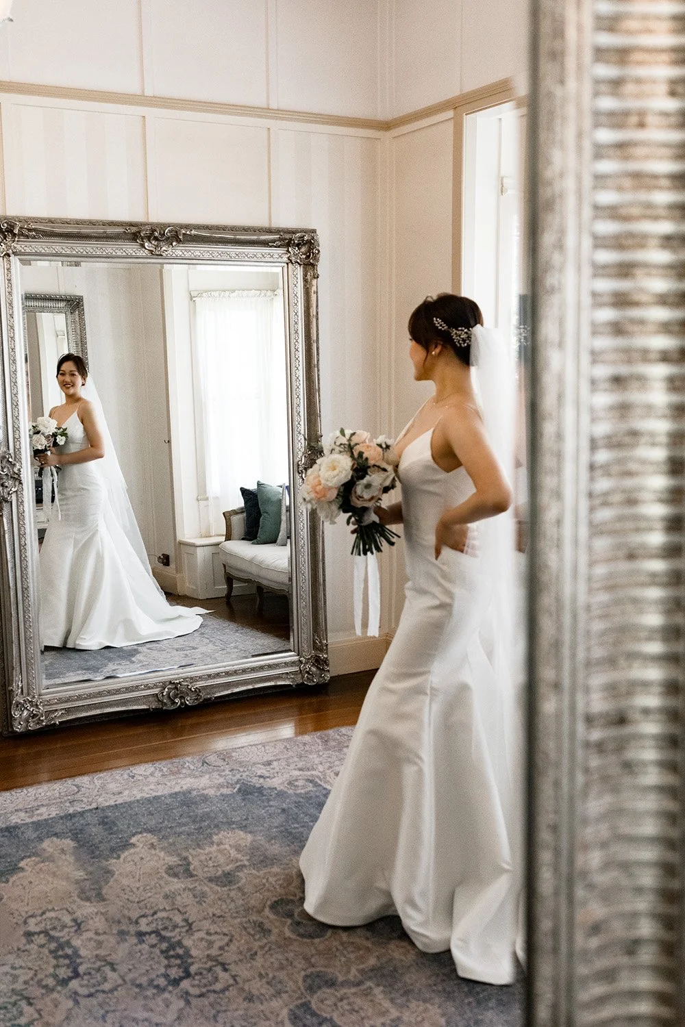 bride Vicky holding a flower and look to herself through the mirror with smell in gabbinbar homestead