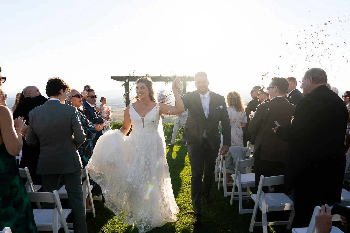 groom Ben and bride Chiarra raising hands up while holding hands together
