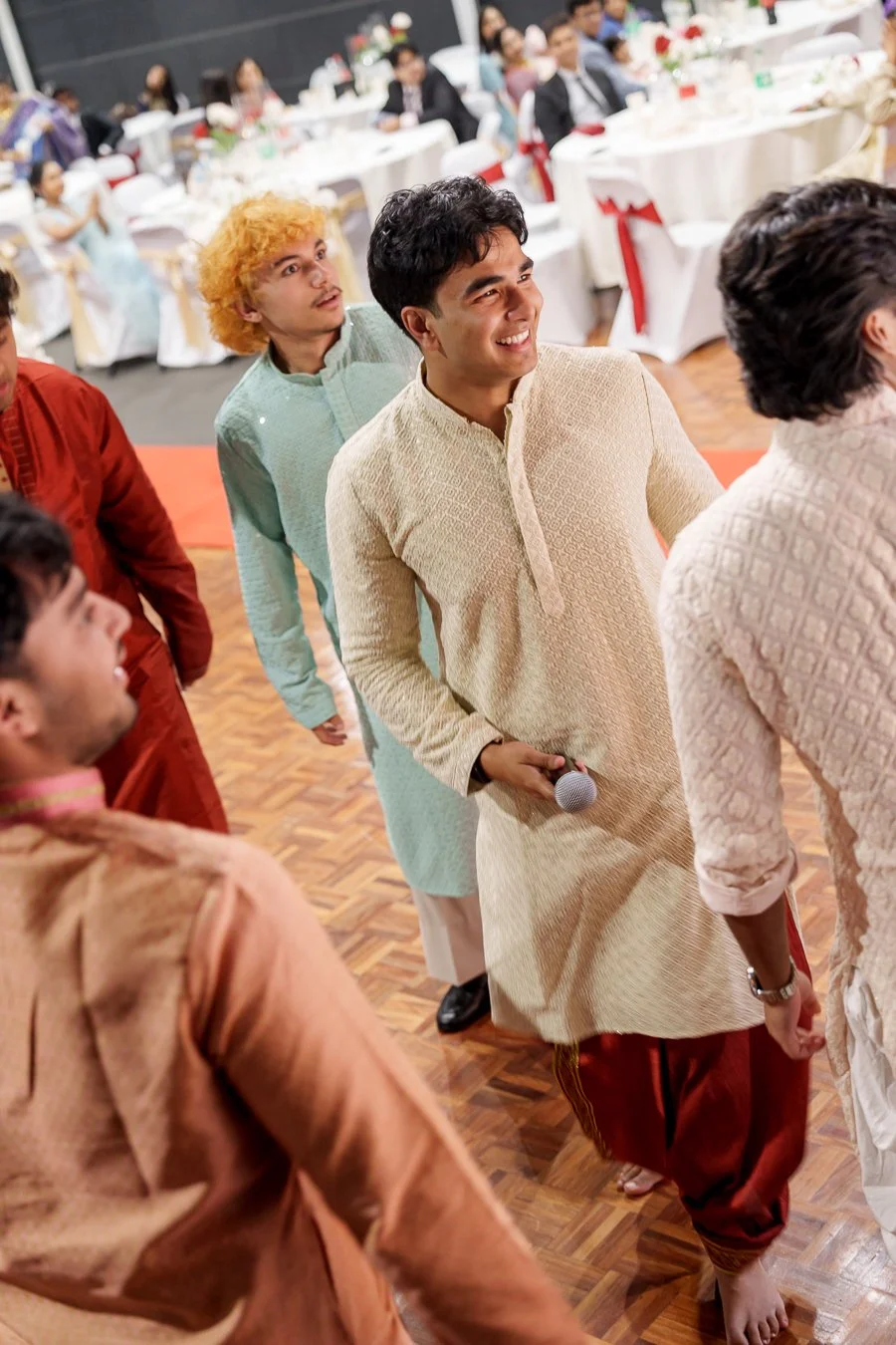 Amrita's brother in law look to the stage with 4 males around him
