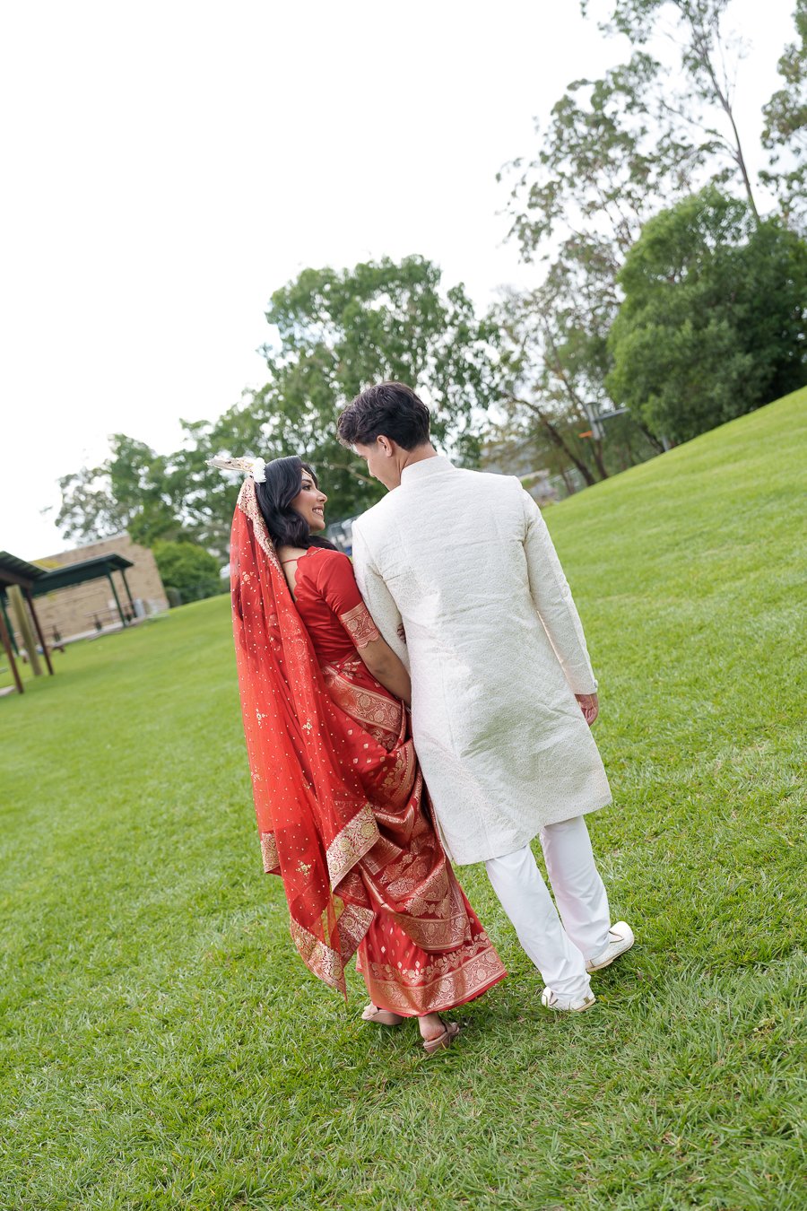 Amrita and Casey look to each other while walking on grass in Logan West Community Centre