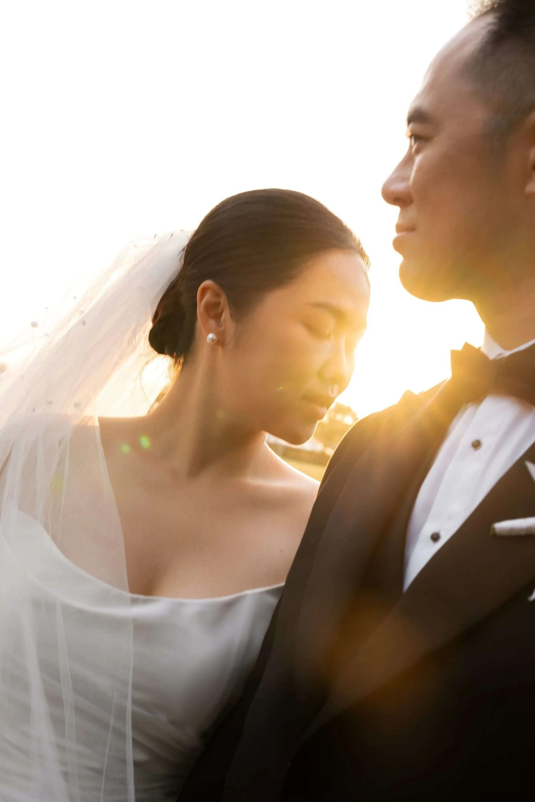 bride Wendy stand next to groom Alex's shoulder and look at it, while sunset hit on their face