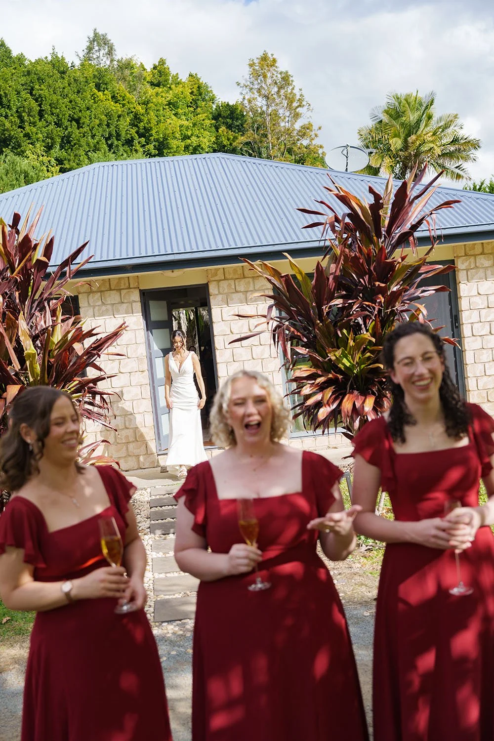 Jasmin in her wedding dress walking out of a door, her brides mates back facing her