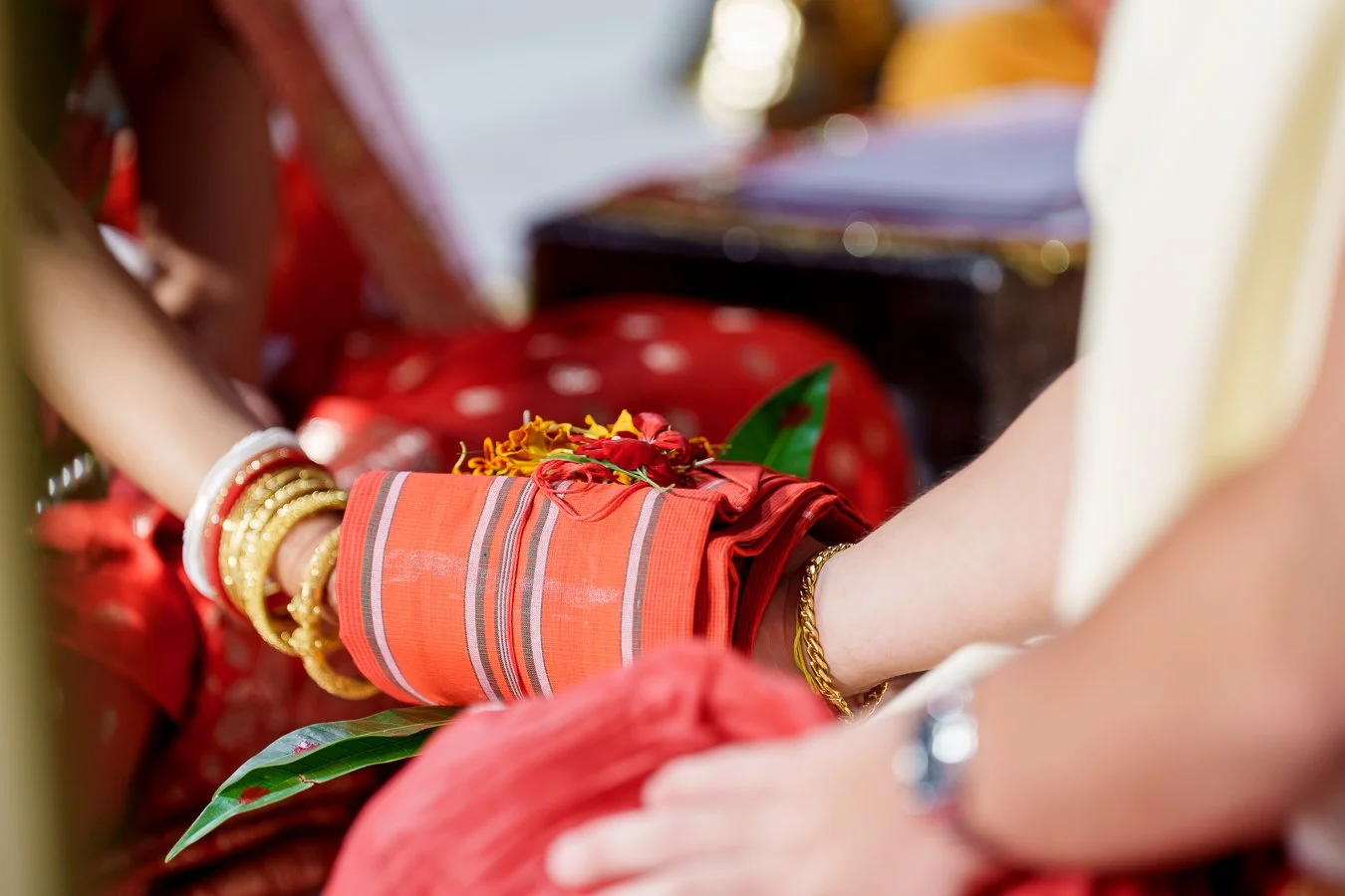 red cloth wraps around Amrita and Casey's hand