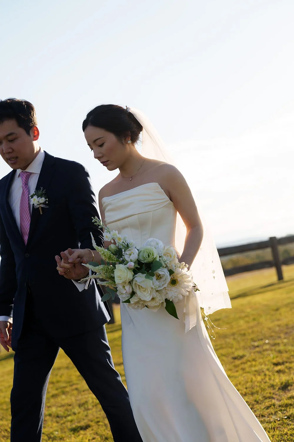 Eric and Flora hands linked, holding each other over and under, looking down at the ground while walking forward