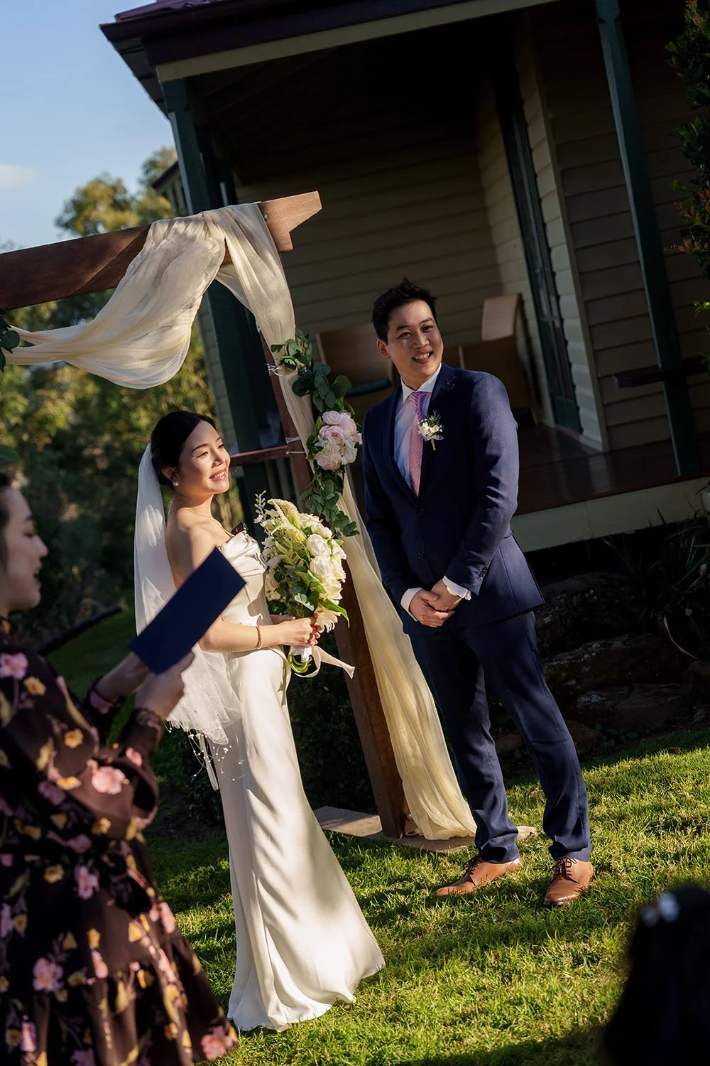 Eric and Flora stand face to face and look to their guests