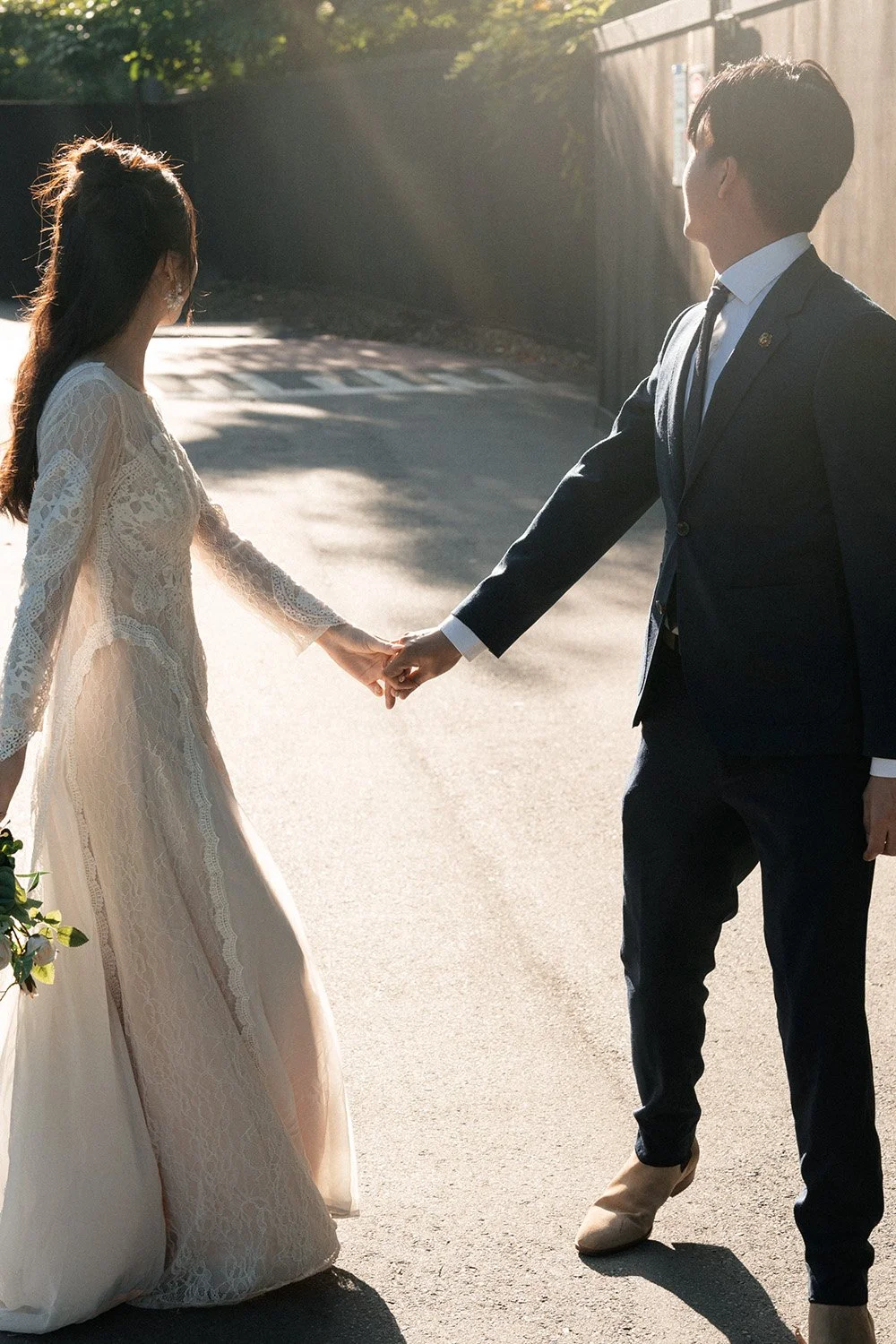 bride and groom holding hands and look back