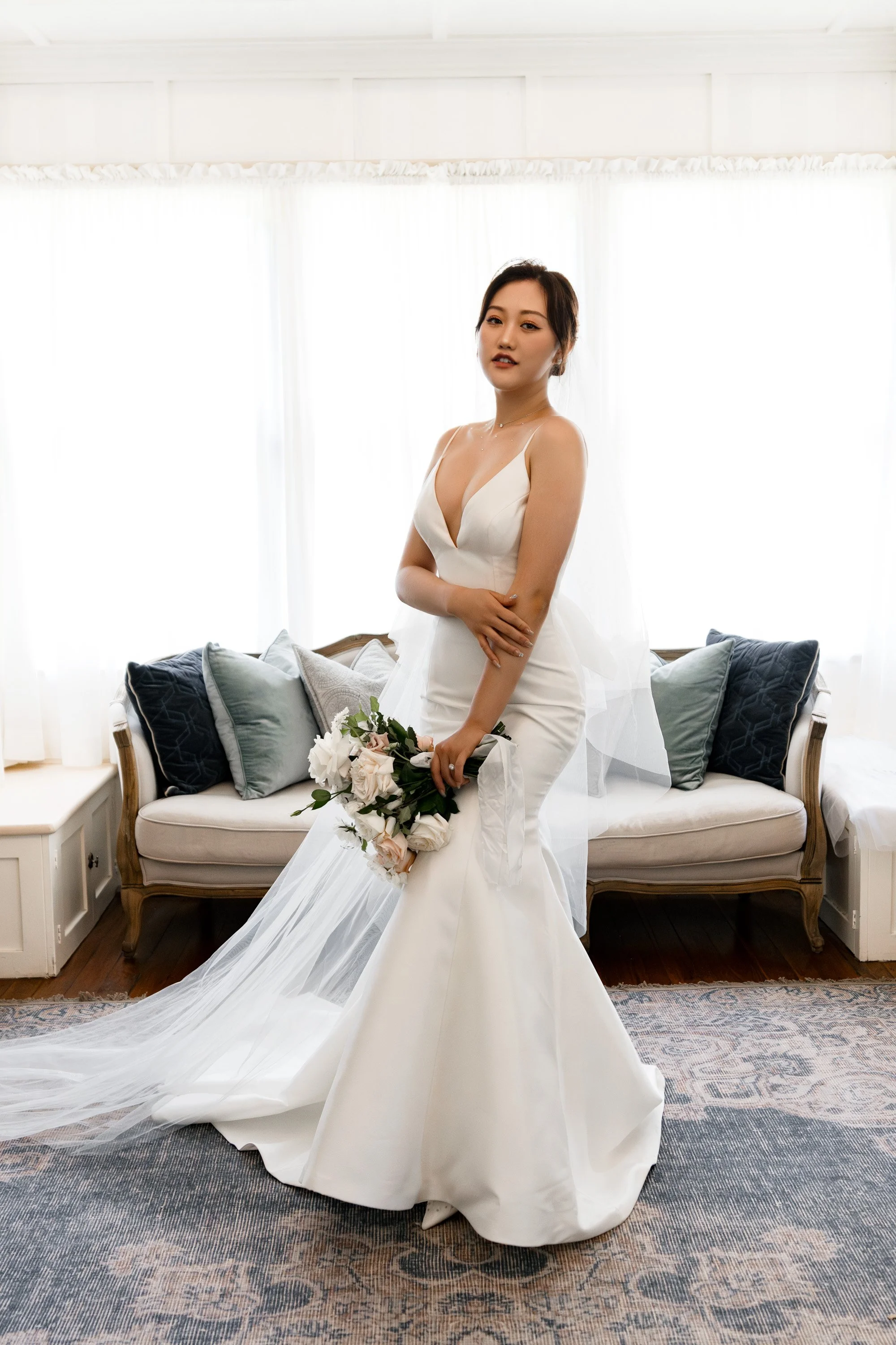 Bride Vicky holding her elbow and looking directly at the Brisbane wedding photographer Whistler. Her pose exudes elegance and confidence, with her soft expression capturing the calm and beauty of her wedding day in this timeless portrait