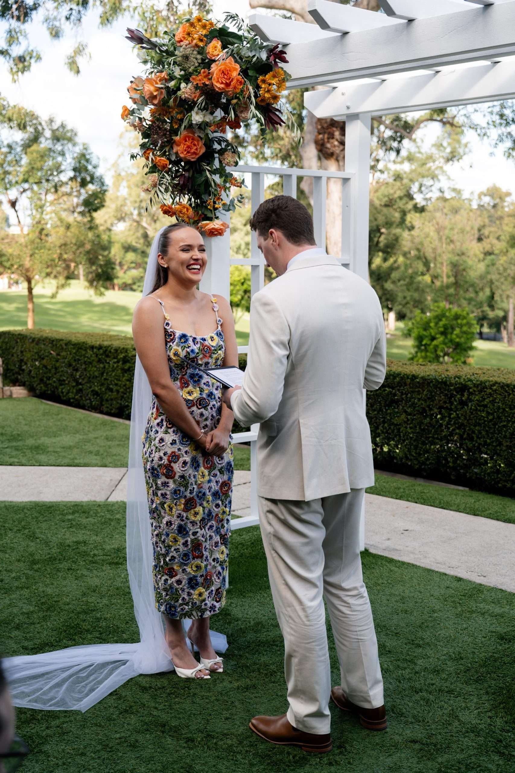 bride laughing standing in front the arbor