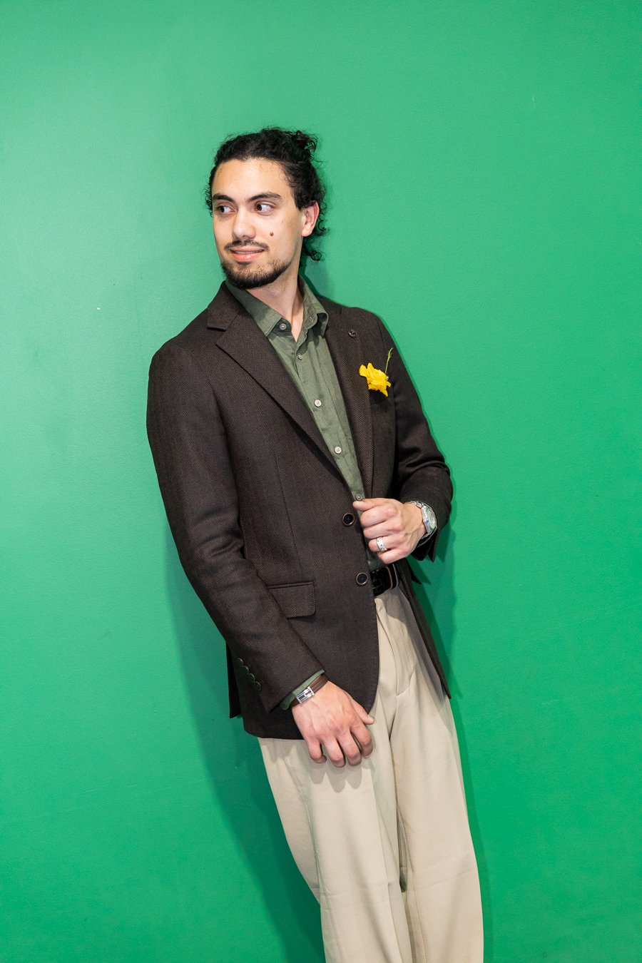 Junaid look off the camera while holding his jacket button