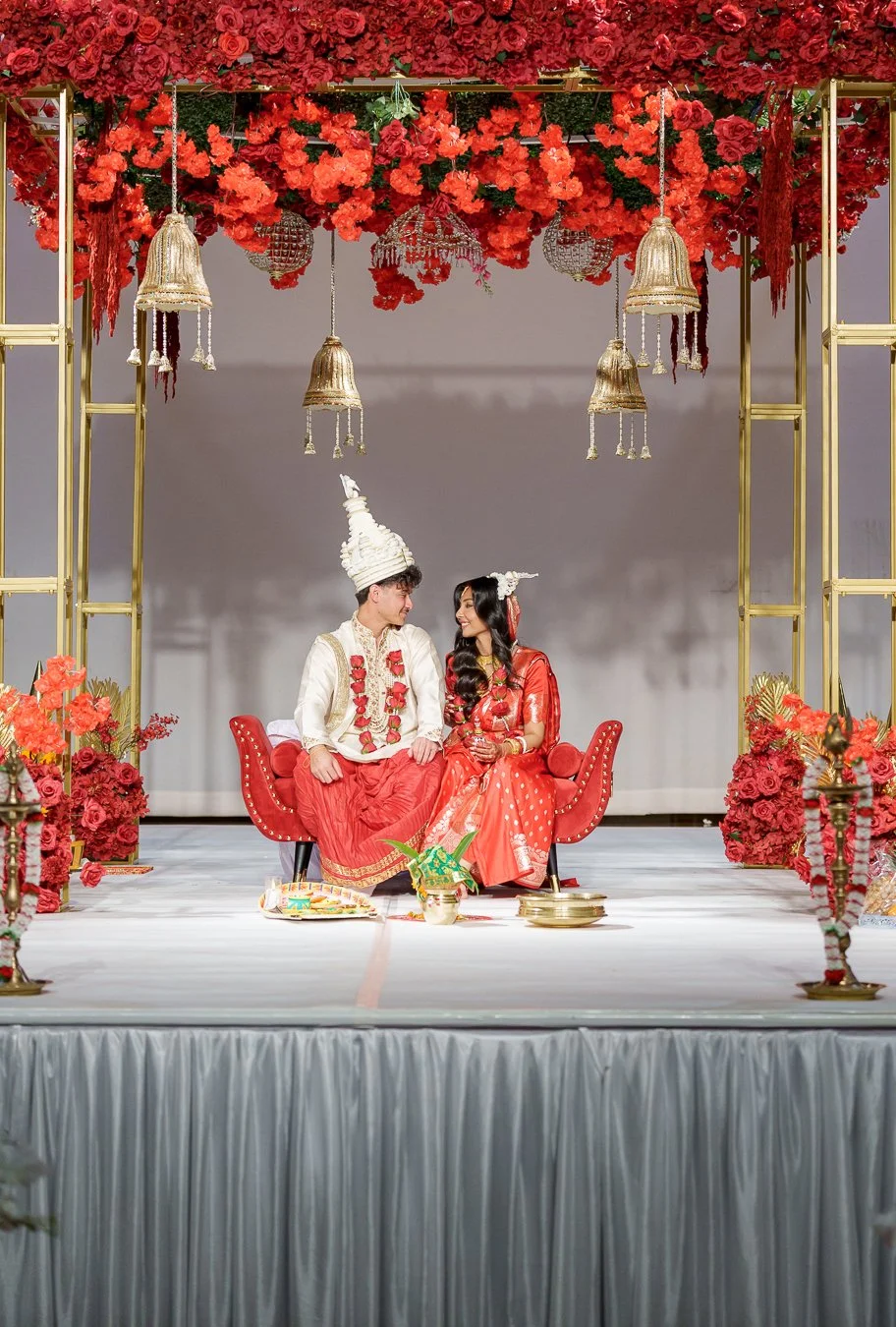 Amrita and Casey look at each other in their traditional outfit while sitting
