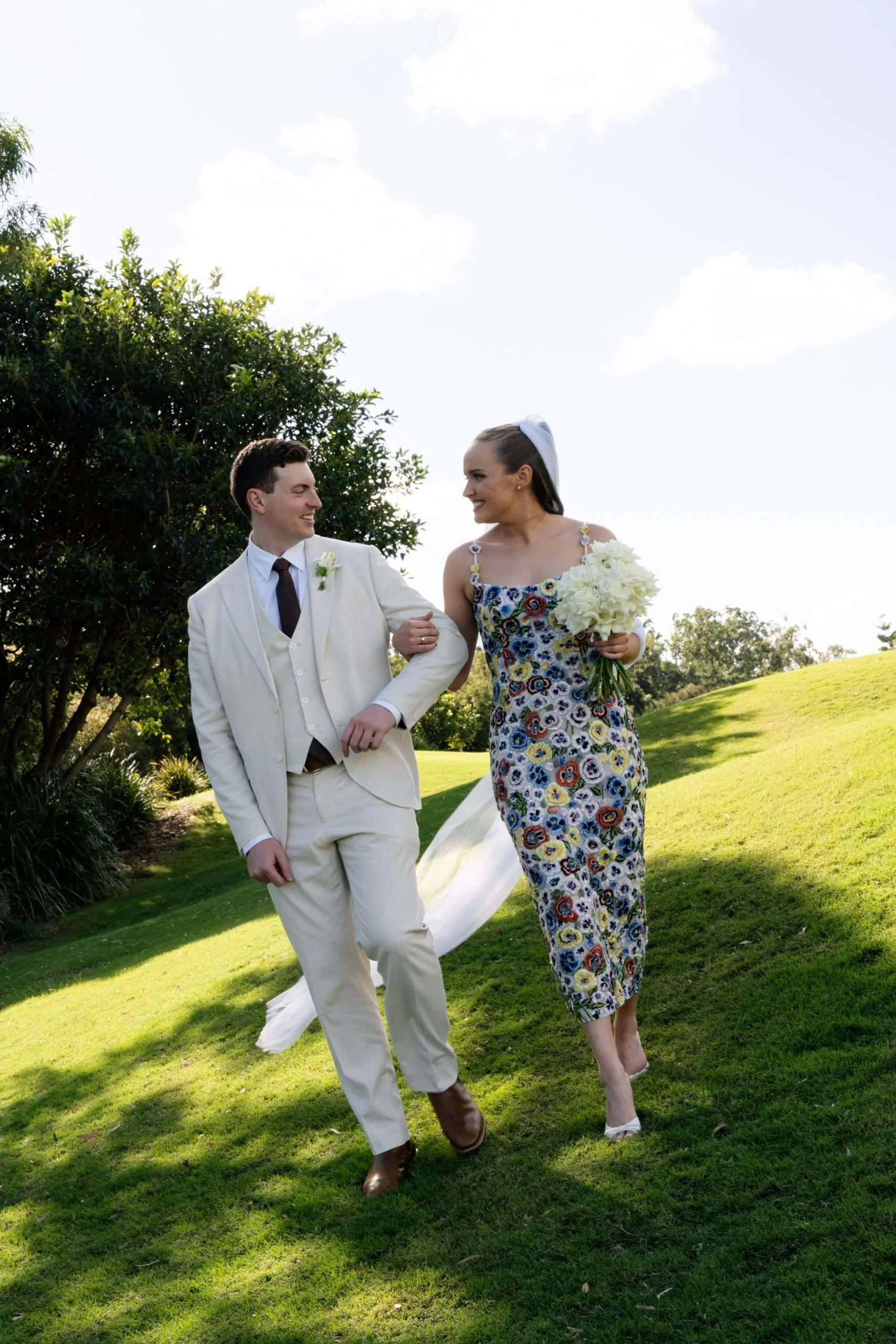 Bride holding the groom’s arm as they walk together, looking at each other.