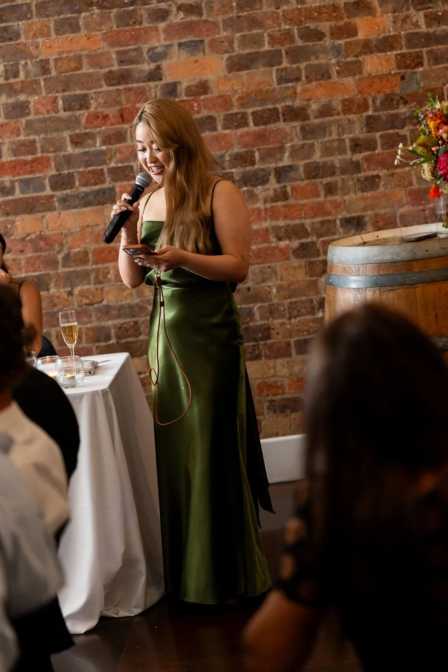 bride Sonya's maid of honour holding a phone speak on a mic making her speech