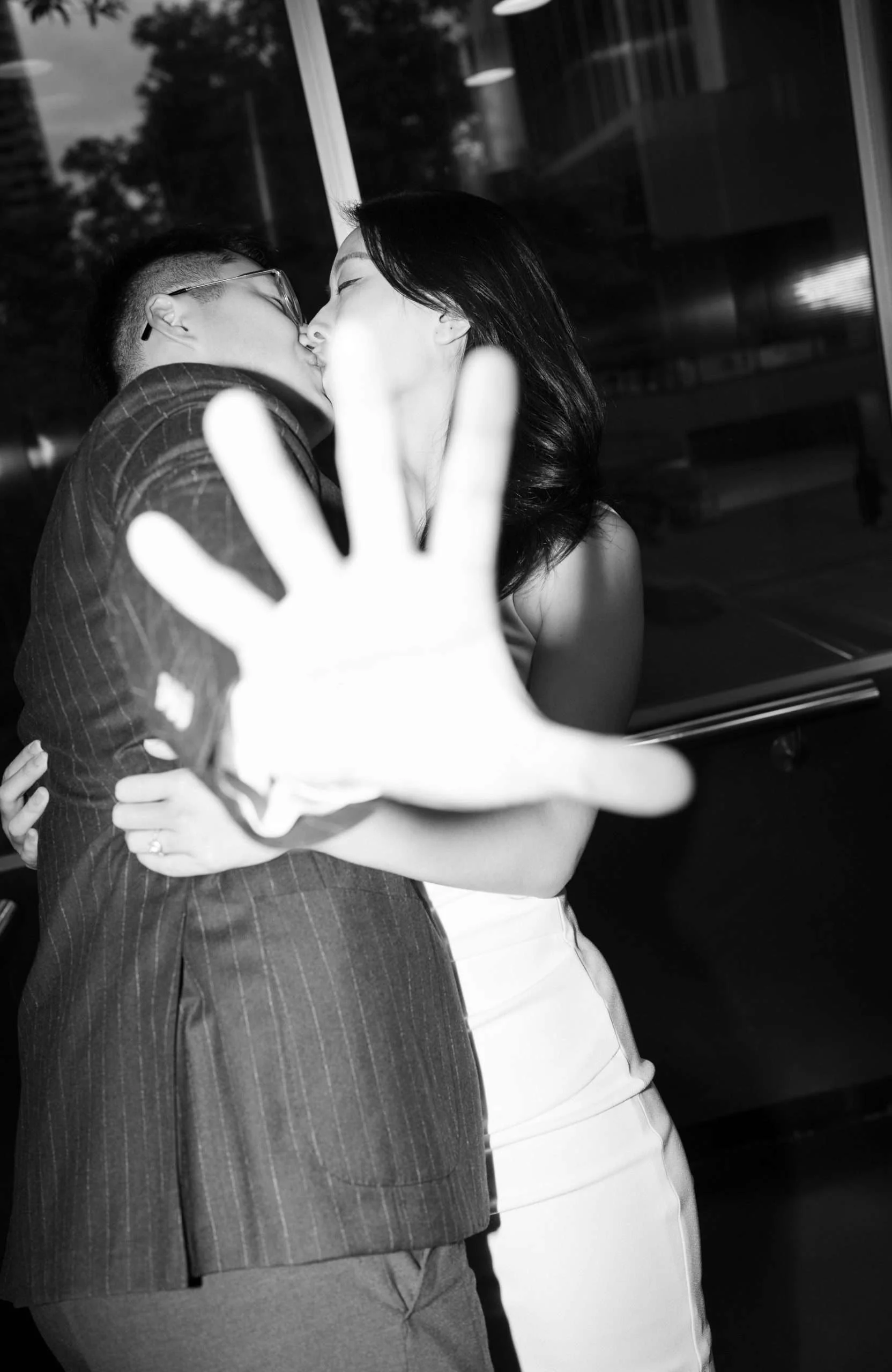 Kath and Dave sharing a kiss inside the elevator, with Dave playfully trying to cover the camera with his hand, creating a candid and lighthearted moment