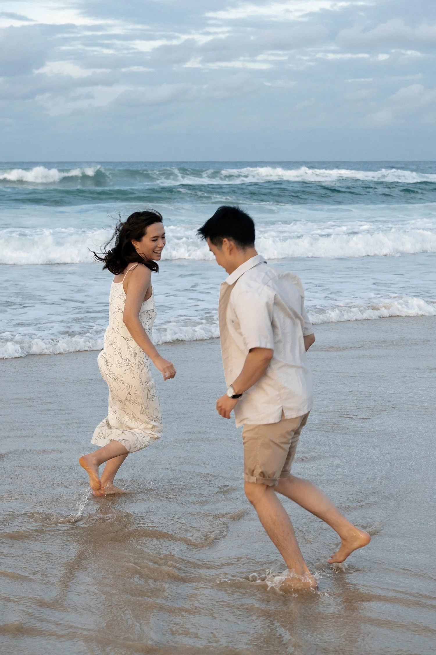 Paul and Krystel running in water in their engagement photography session in Currumbin Rock