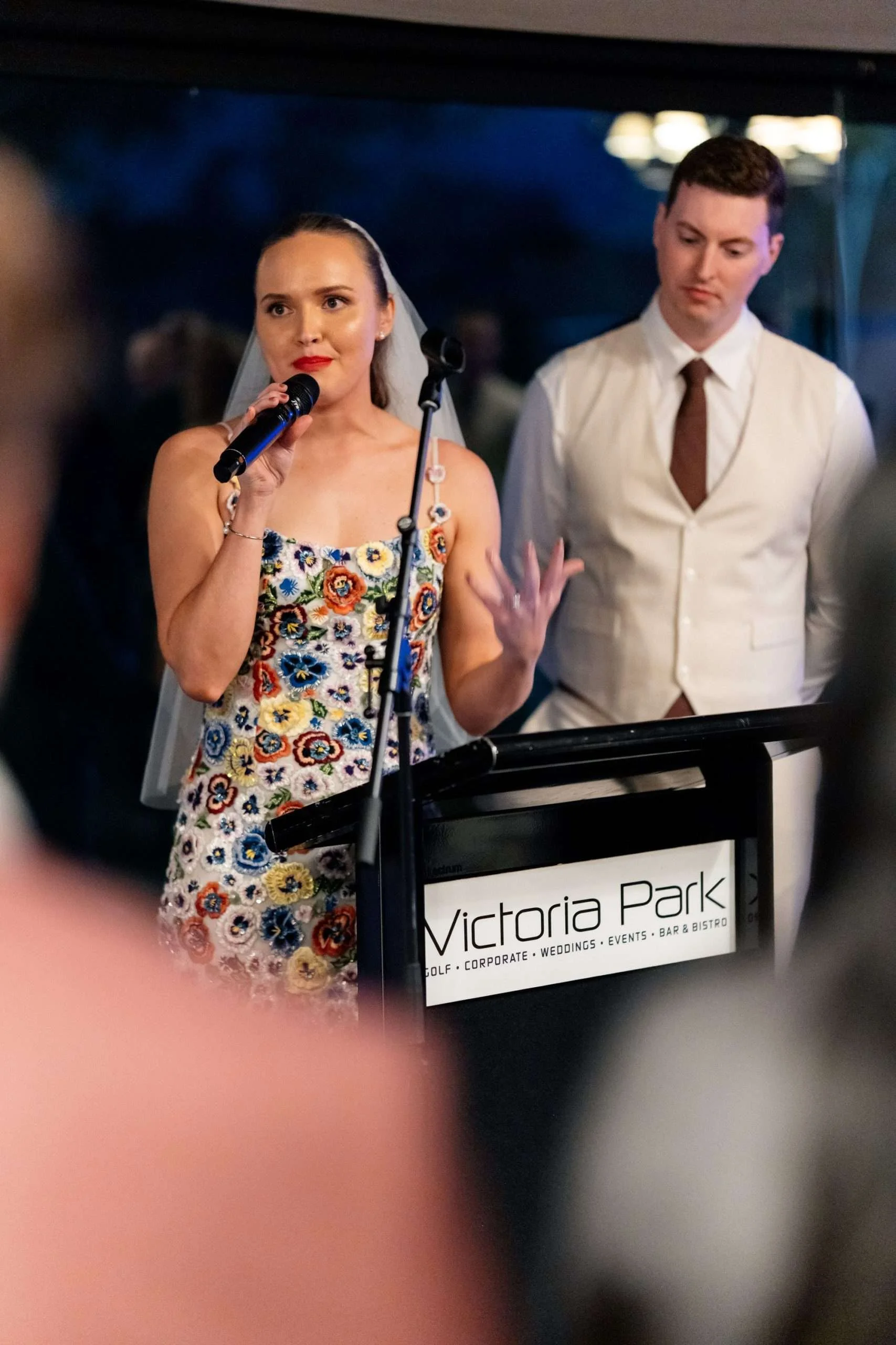 bride Charlotte speak on a mic in Victoria Park garden marquee reception room