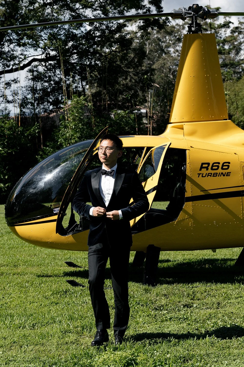 groom Brus Botton up when walking in front of a yellow helicopter