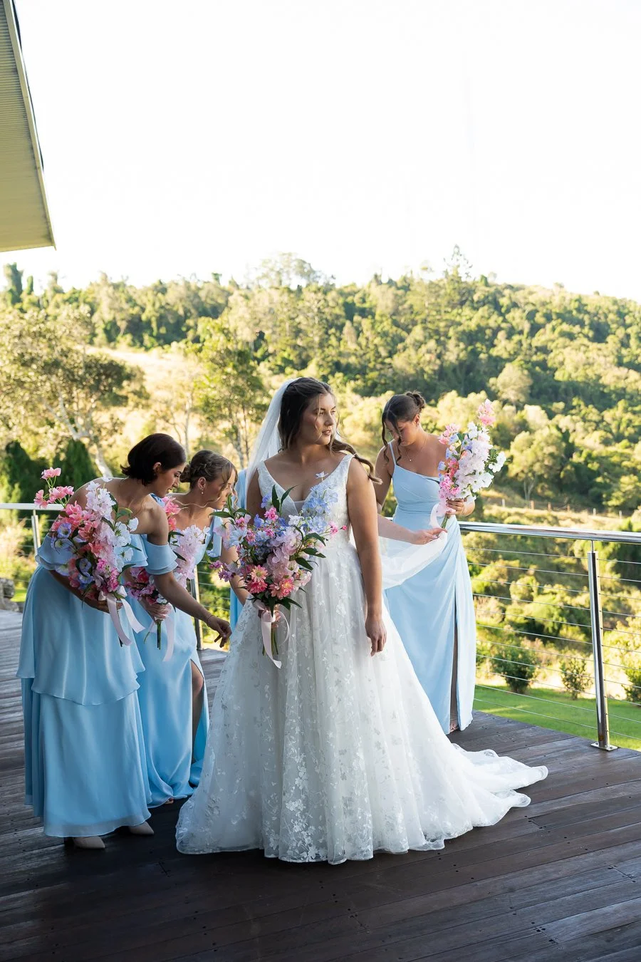 brides mates in their light blue dress and adjusting Chiarra's wedding dress