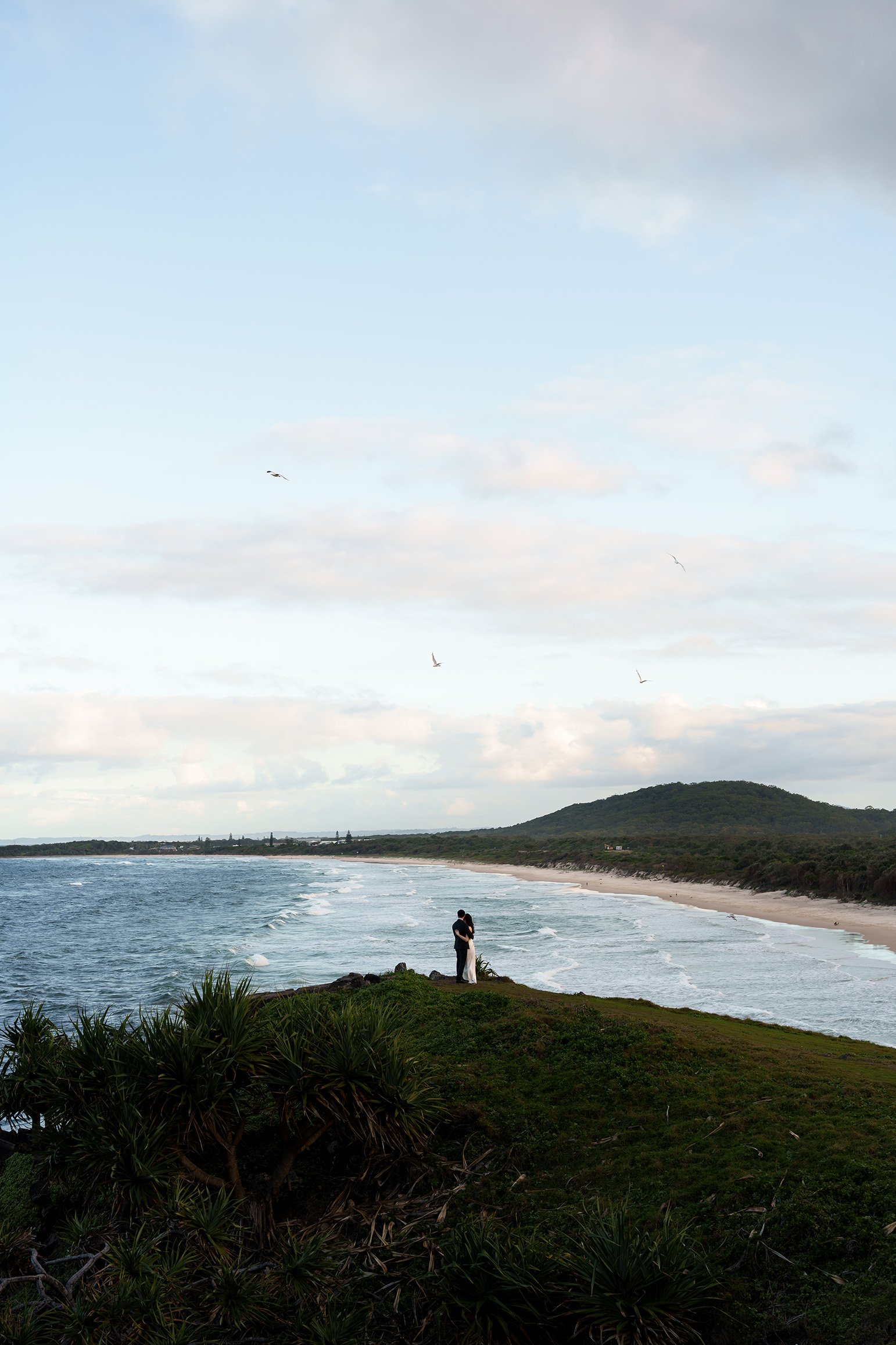They held and leanning each other, looking out at the sea. birds flying in the sky