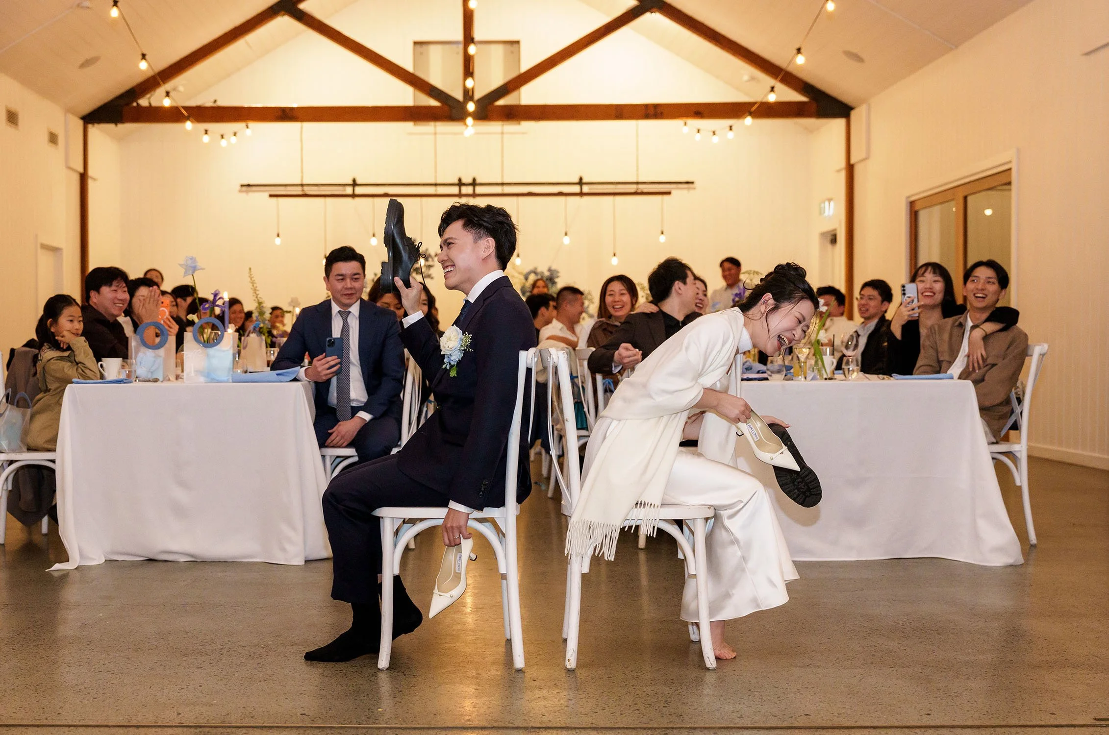 Michael and Lisa sitting on the chair raising their shoes when playing the shoe game