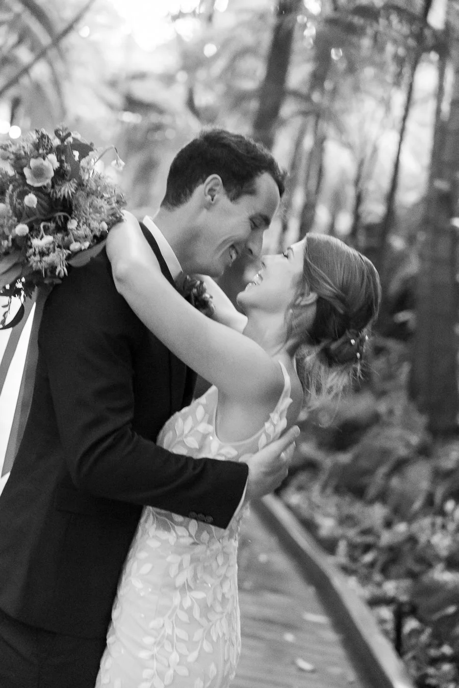 The bride and groom smile as they hold each other