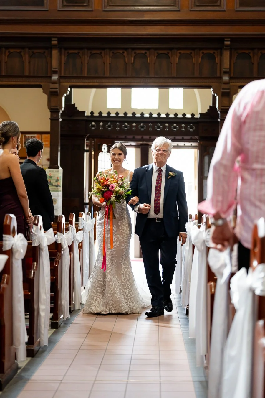 The bride walked into the church arm in arm with her father