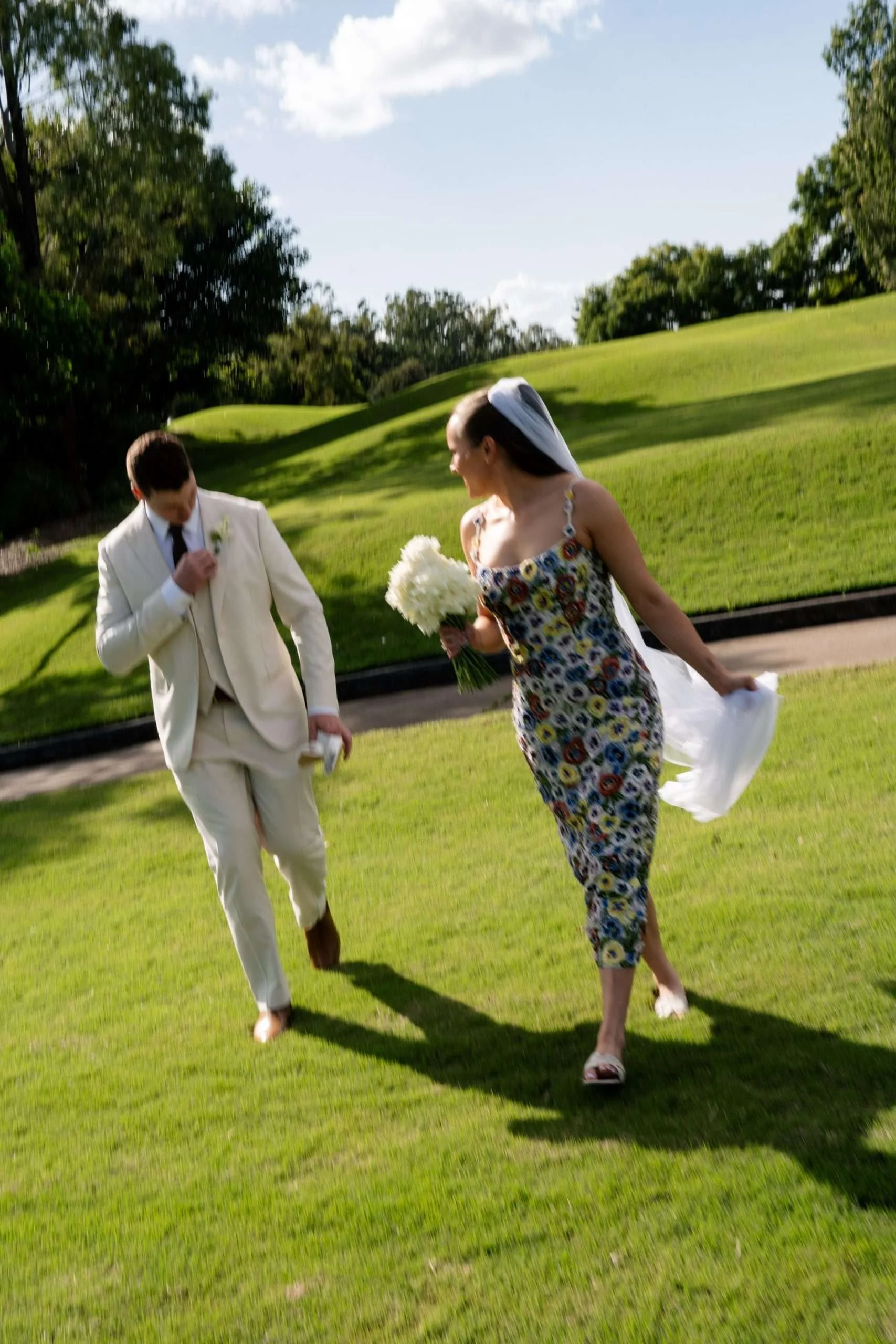bride and groom walking together on grass with blur background