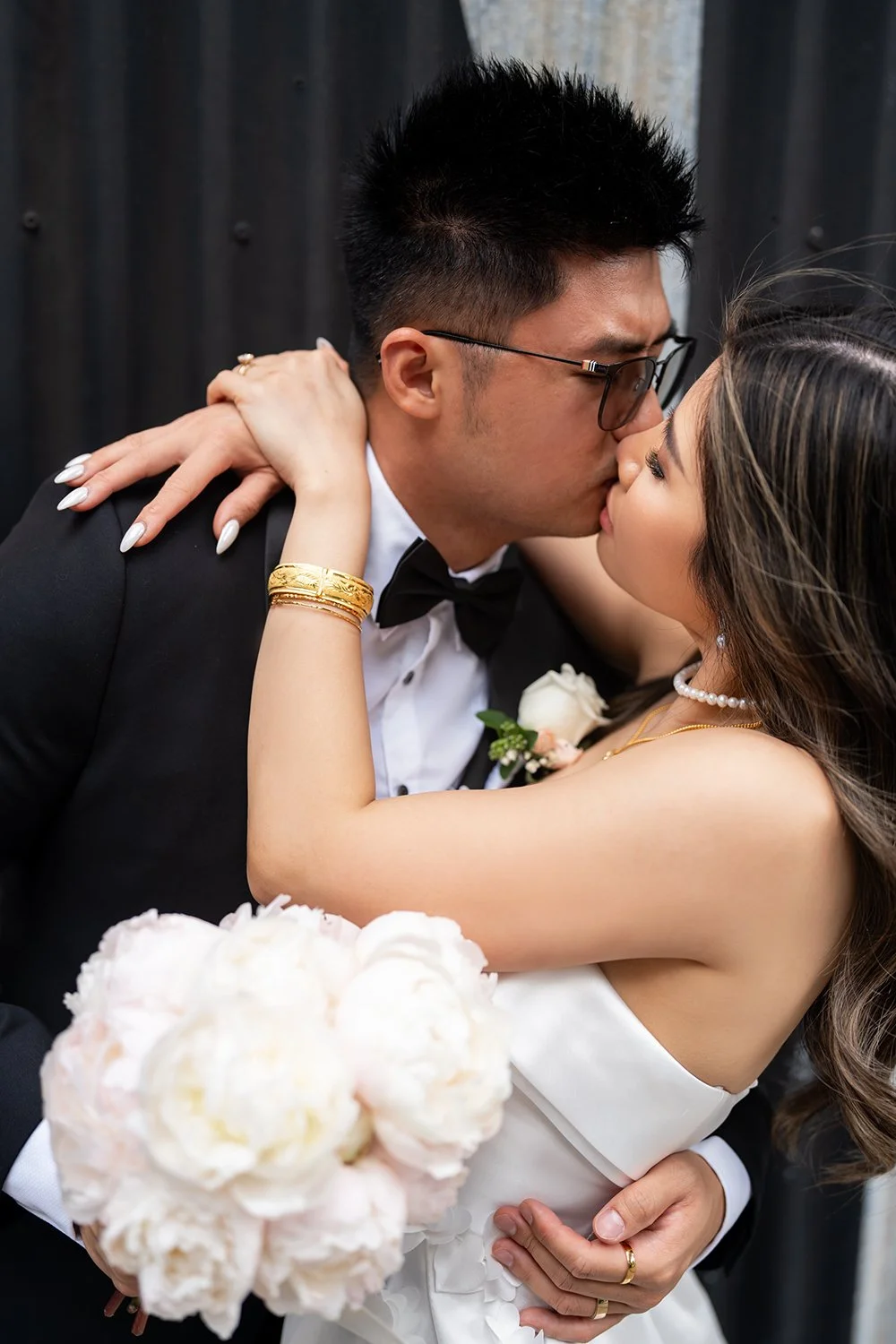 Bride Tiffy holding the groom Kai's neck as she kisses him tenderly, capturing a moment of deep affection and love. The intimate gesture between the couple radiates warmth and romance, showcasing their connection on their special day.