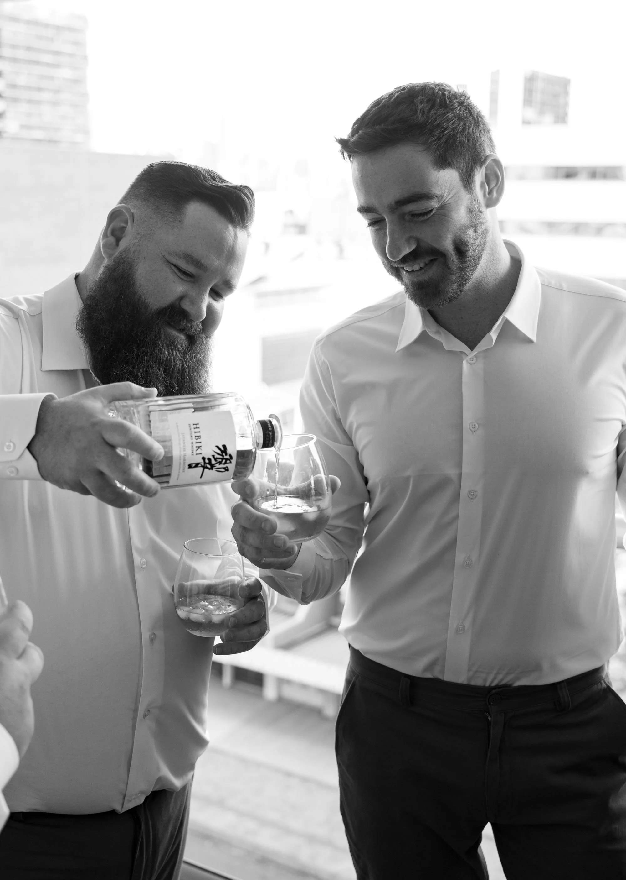 Best man pouring wine for groom Thomas, sharing a thoughtful moment of camaraderie as they prepare for the wedding celebration