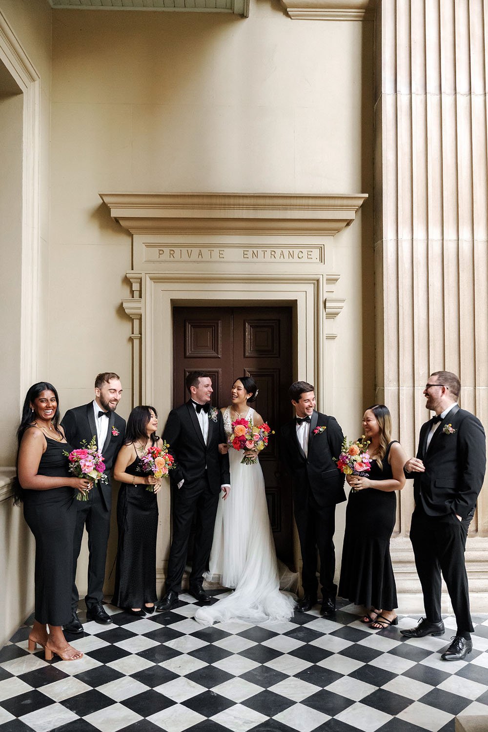bride Nori and groom Cliffe laughing with their bridal party